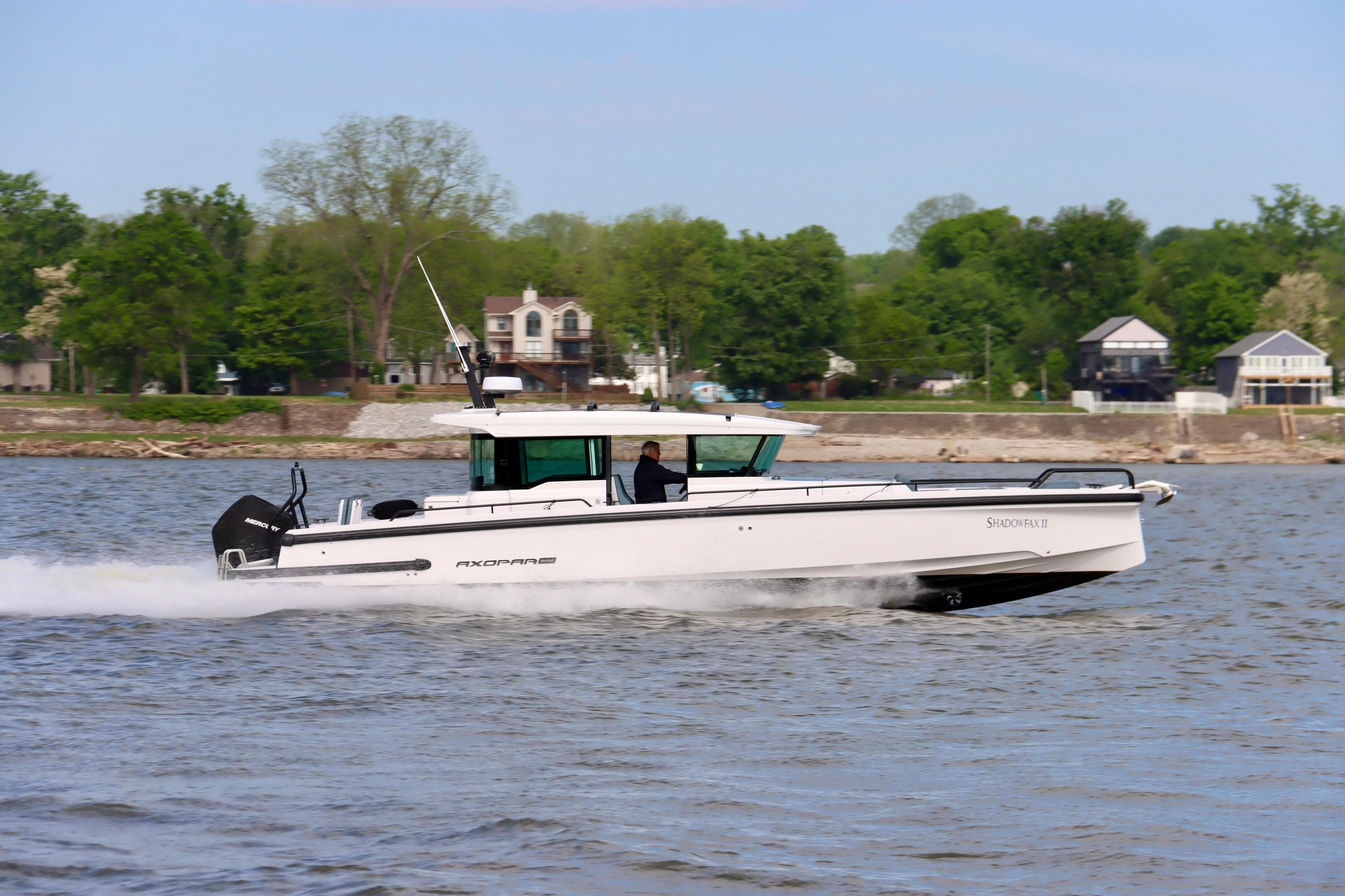 2022 Axopar 37 XC Cross Cabin cruising on a river with lush green shoreline.
