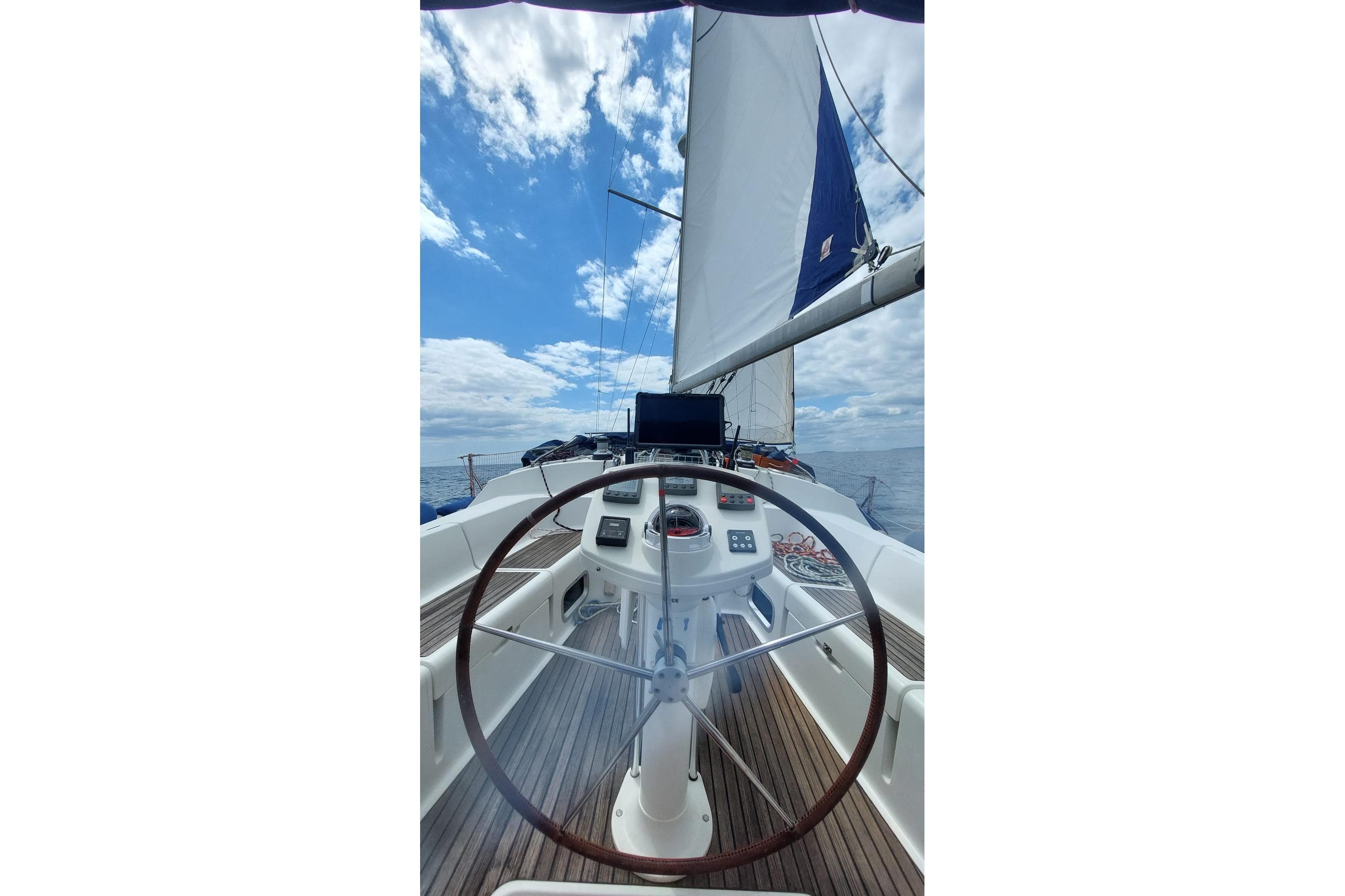 Cockpit view of 2002 Jeanneau Sun Odyssey 43 DS sailing under blue skies.