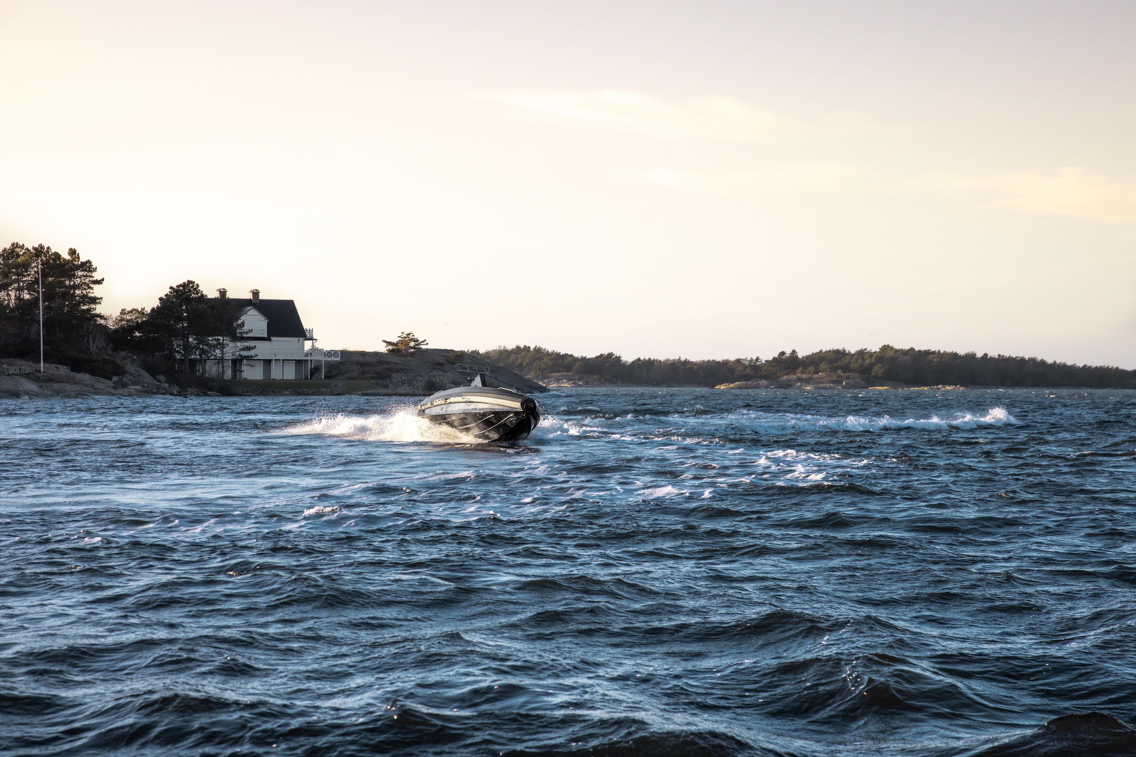 2026 Iron 767 T-top boat cruising on a scenic coastal waterway near a house.