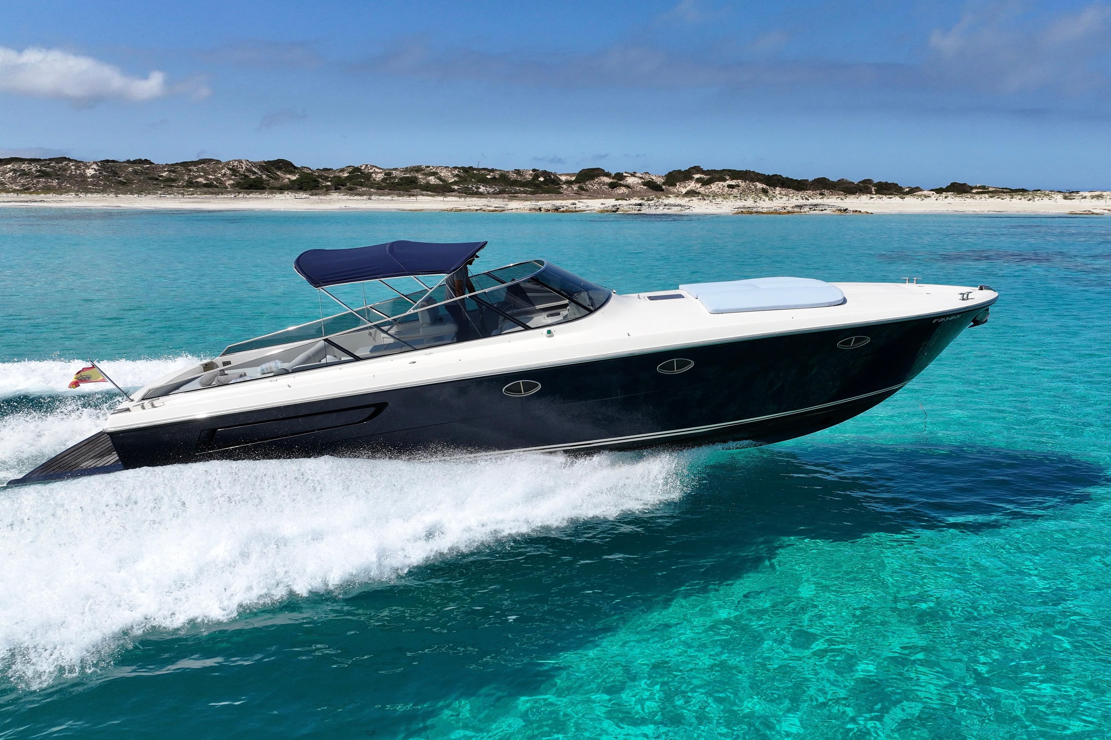 2008 Itama 40 yacht cruising on clear turquoise waters near a sandy shoreline.