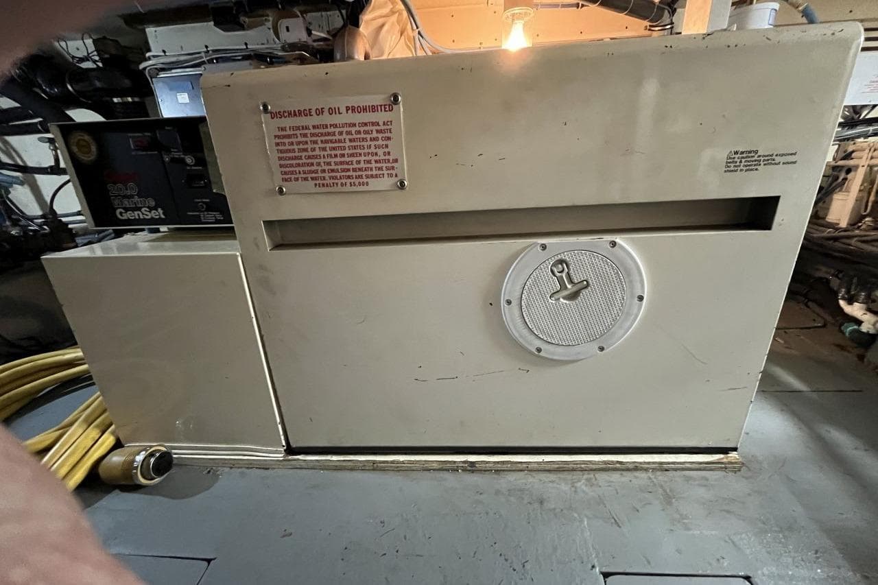 Engine room of 1991 Hatteras 61 Motor Yacht with generator and warning sign.