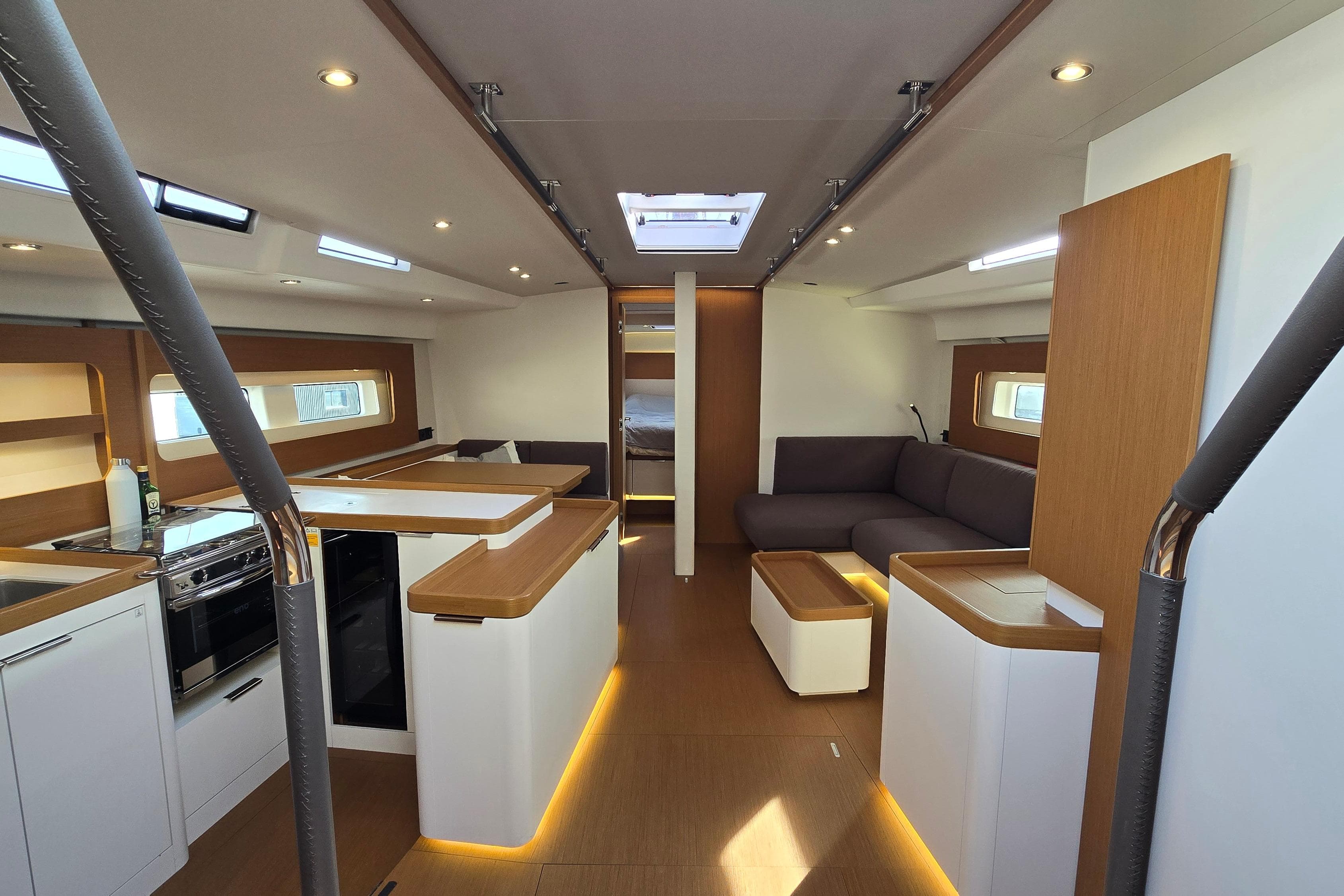 Luxurious interior of 2022 Beneteau First 53 yacht, featuring modern kitchen and cozy seating area.