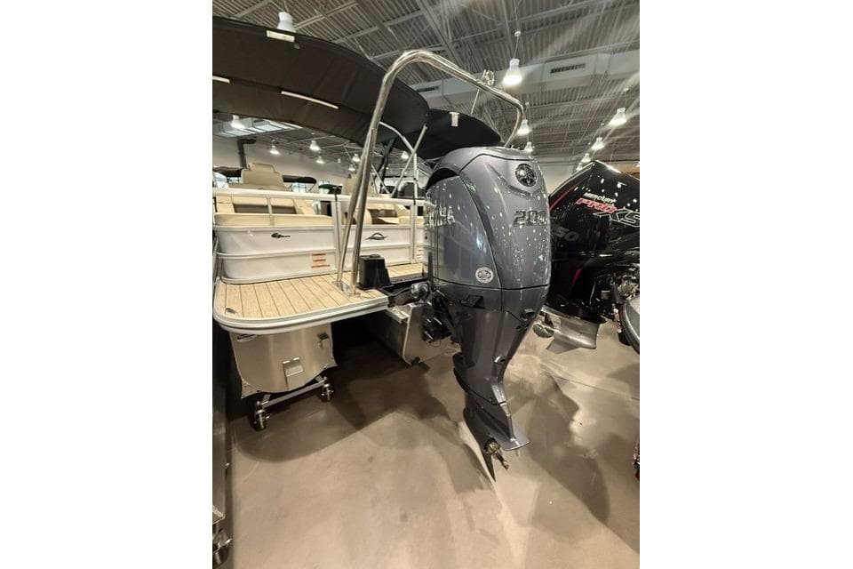 2026 SunCatcher Fusion 322SS boat with powerful outboard motor in showroom setting.