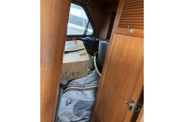 1988 Kadey Krogen 42 interior storage with cardboard box and rolled items.