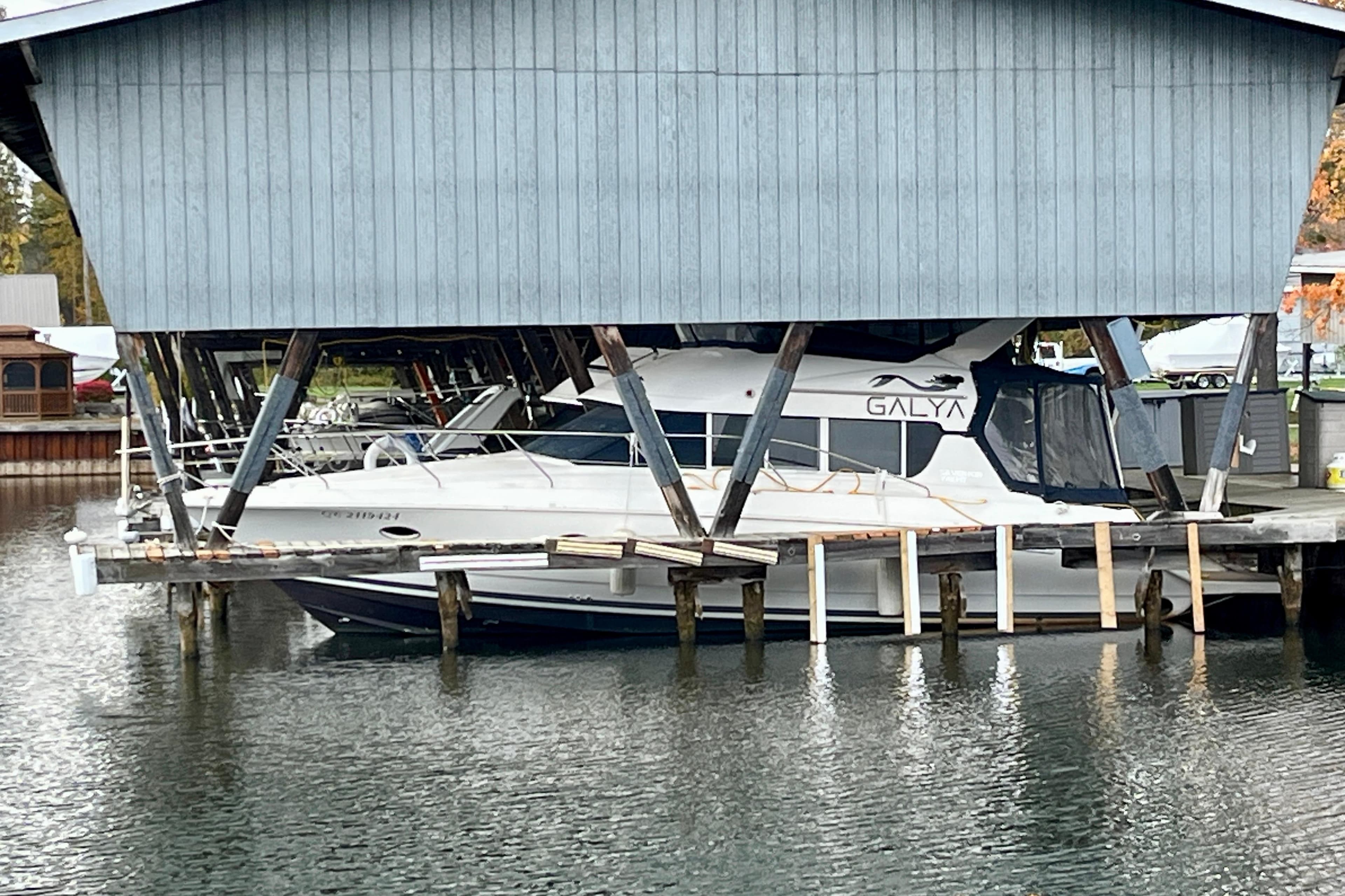 1997 Silverton 362 Sedan Cruiser docked under a wooden boathouse.
