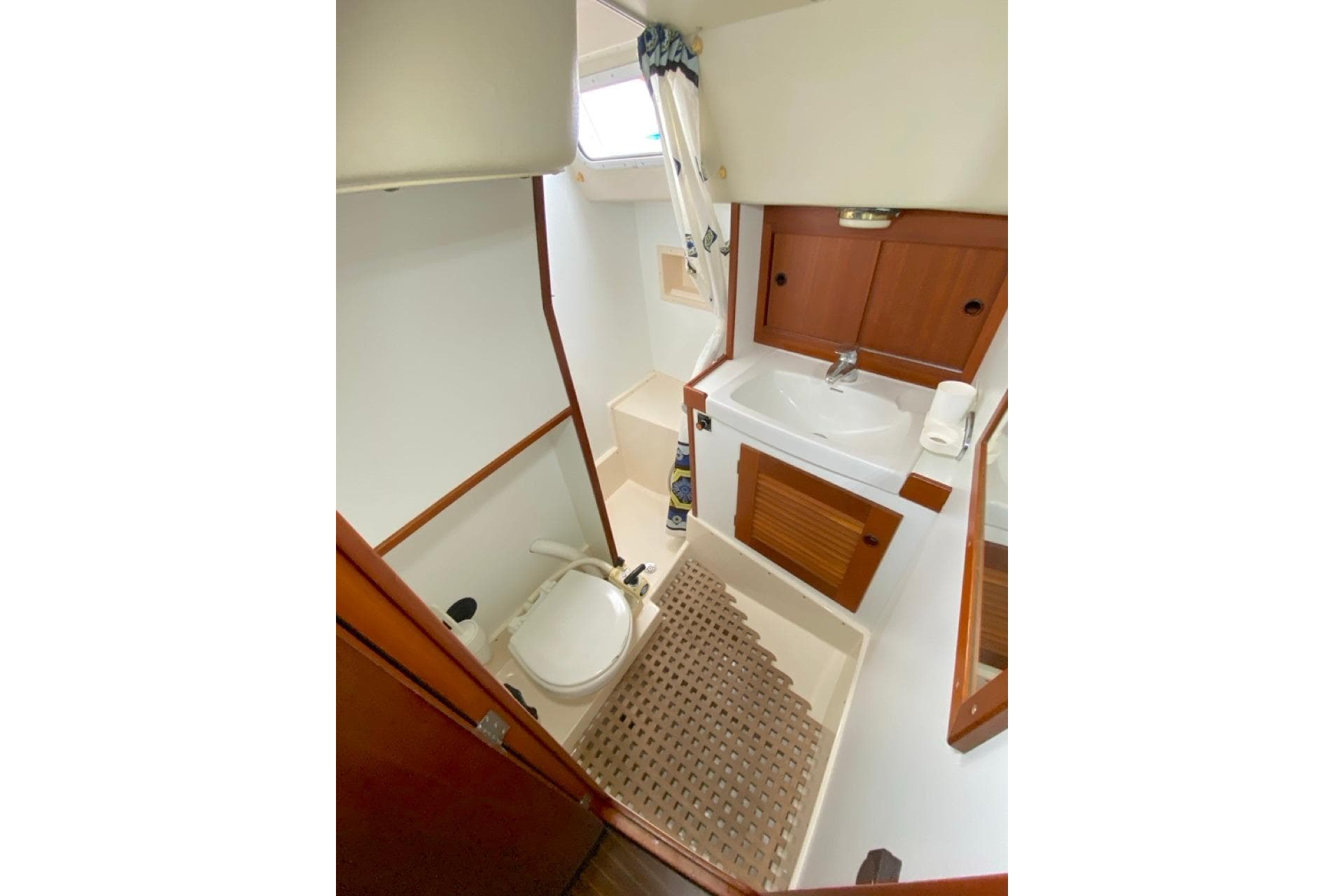 Bathroom interior of 1992 Hallberg-Rassy 45 yacht with sink, toilet, and wooden cabinetry.