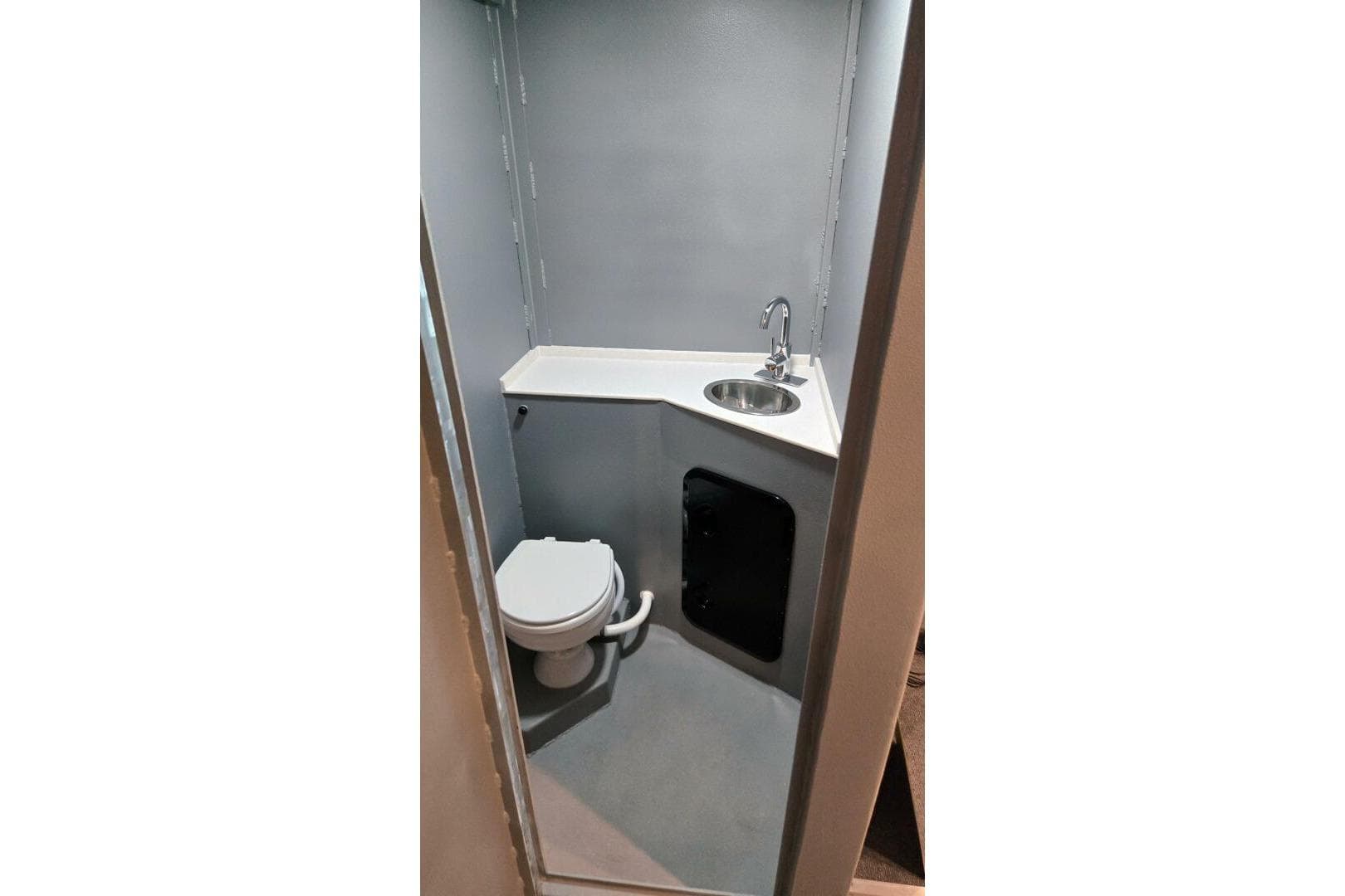 Compact bathroom in a 1990 custom rebuilt dive boat, featuring a toilet and sink.