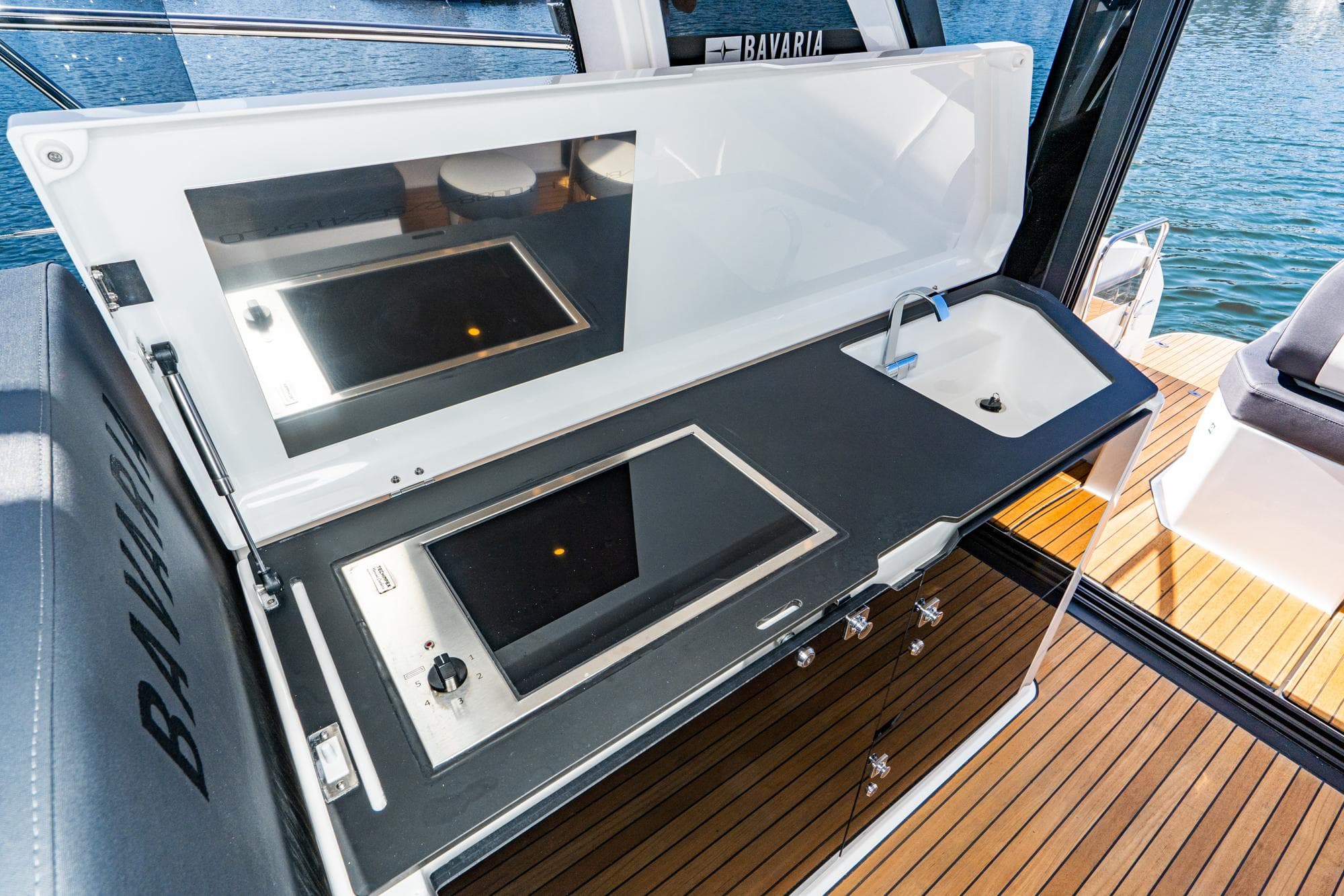 2024 Bavaria SR41 yacht kitchen with stove and sink, featuring sleek design and wooden deck.