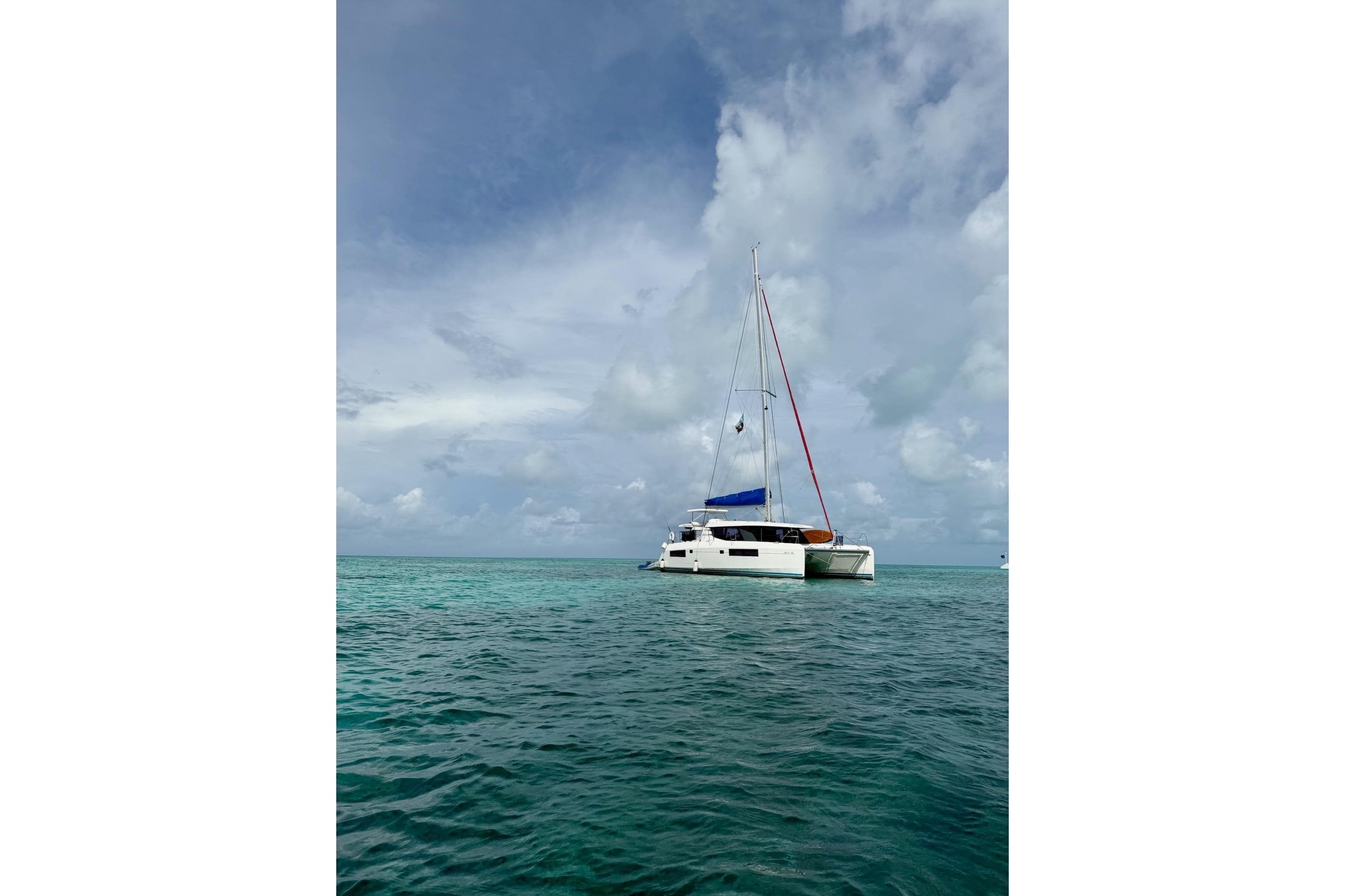 2018 Leopard 45 catamaran sailing on turquoise ocean under cloudy sky.