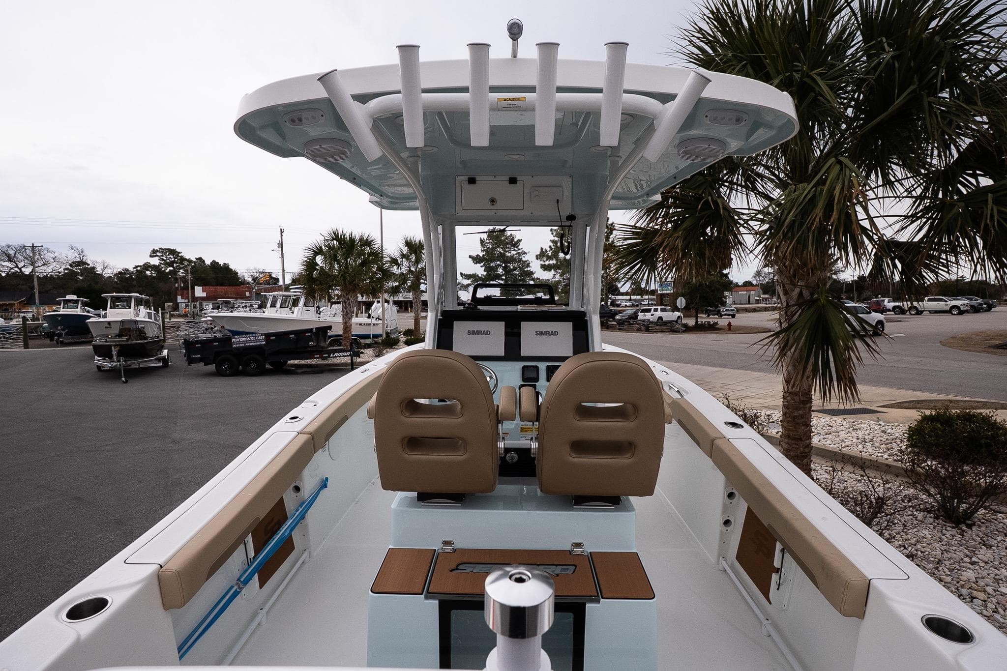 2026 Sea Pro 245FLXR Sandbar boat interior with helm, seats, and palm trees in the background.