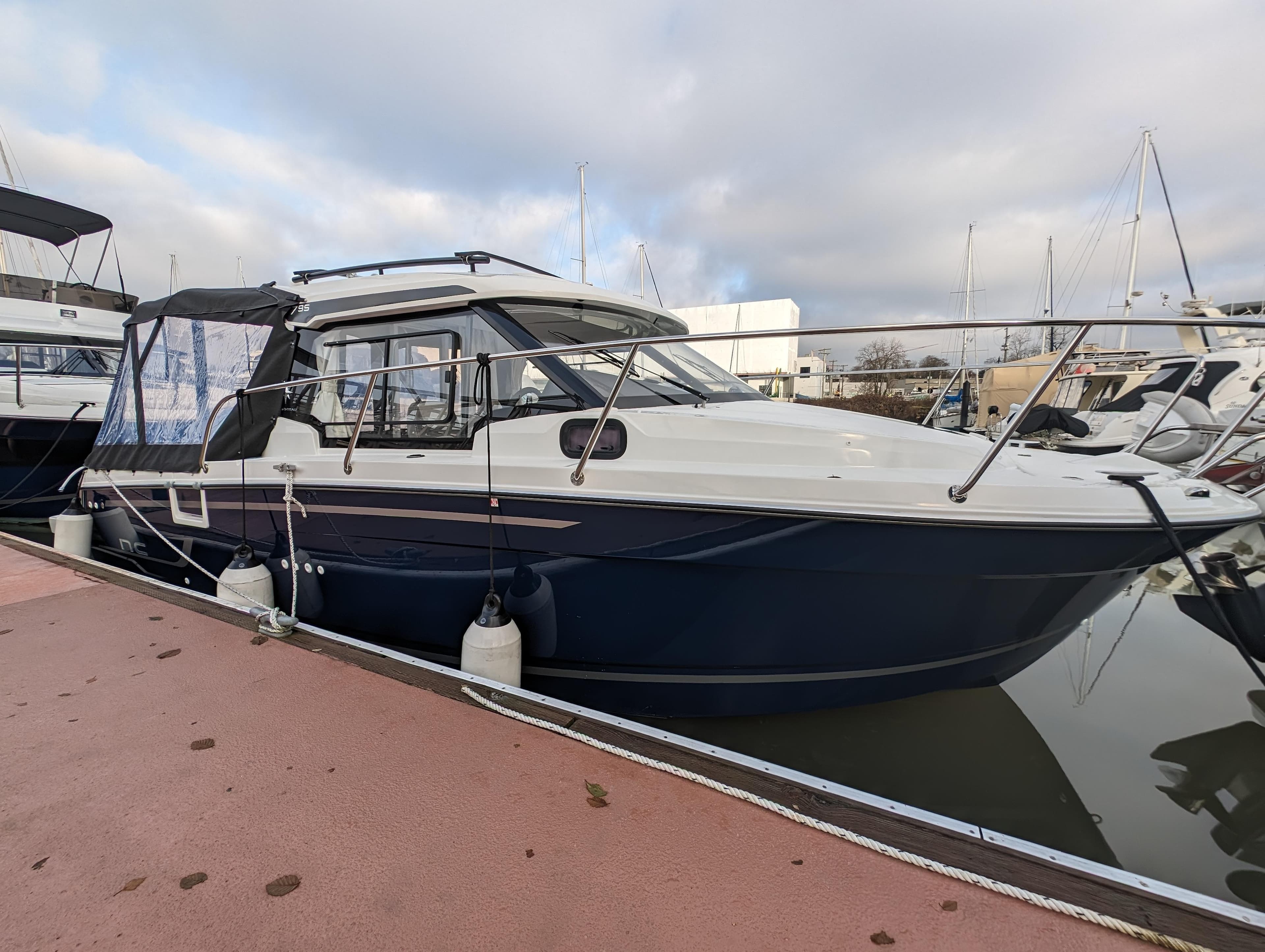 2024 Jeanneau 795 S2 boat docked at marina under cloudy sky.