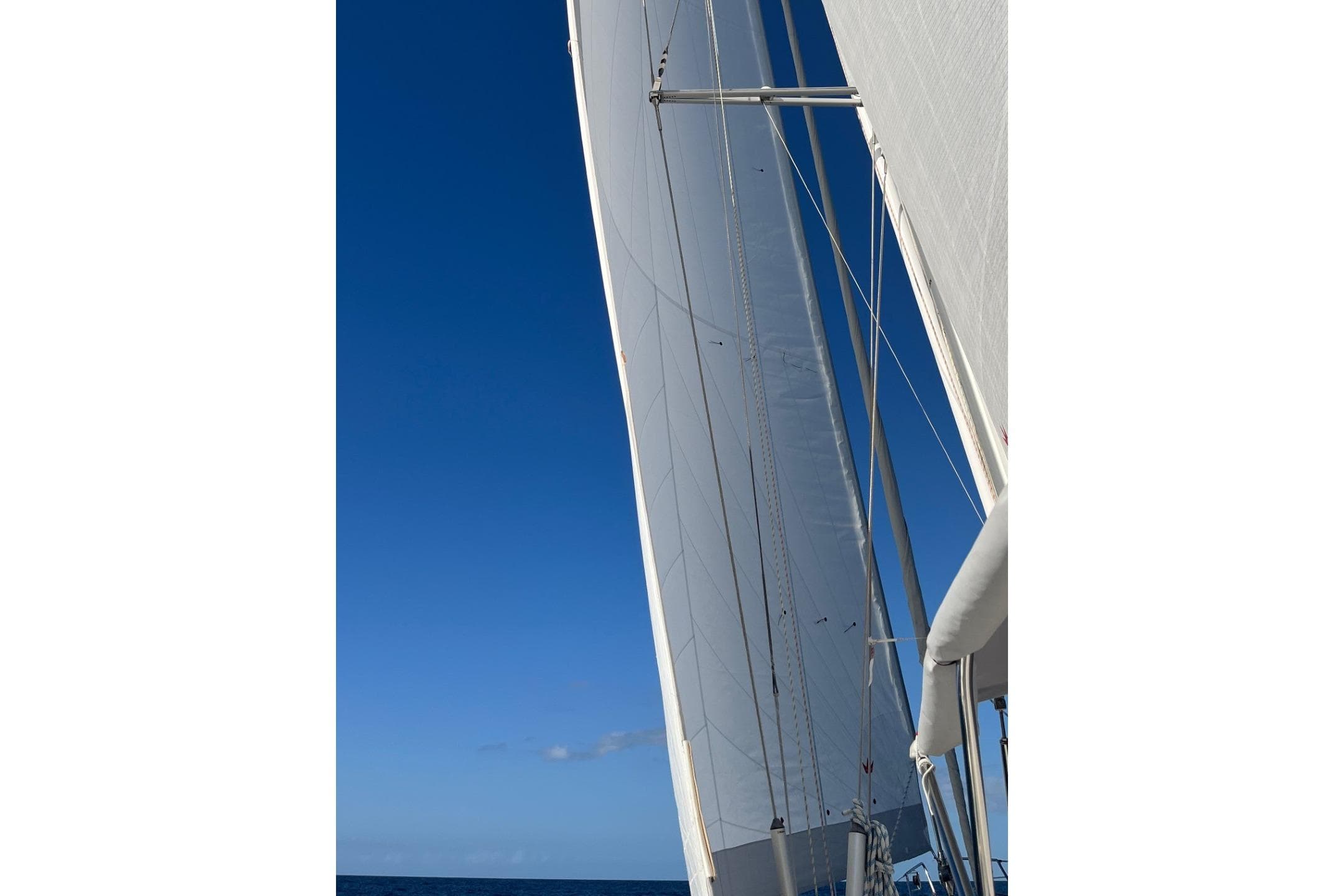 Sails of a 2009 Hallberg-Rassy 54 yacht against a clear blue sky.