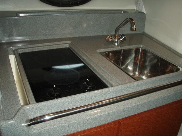2003 Wellcraft 3300 Martinique galley with sink and stovetop, featuring sleek countertops.