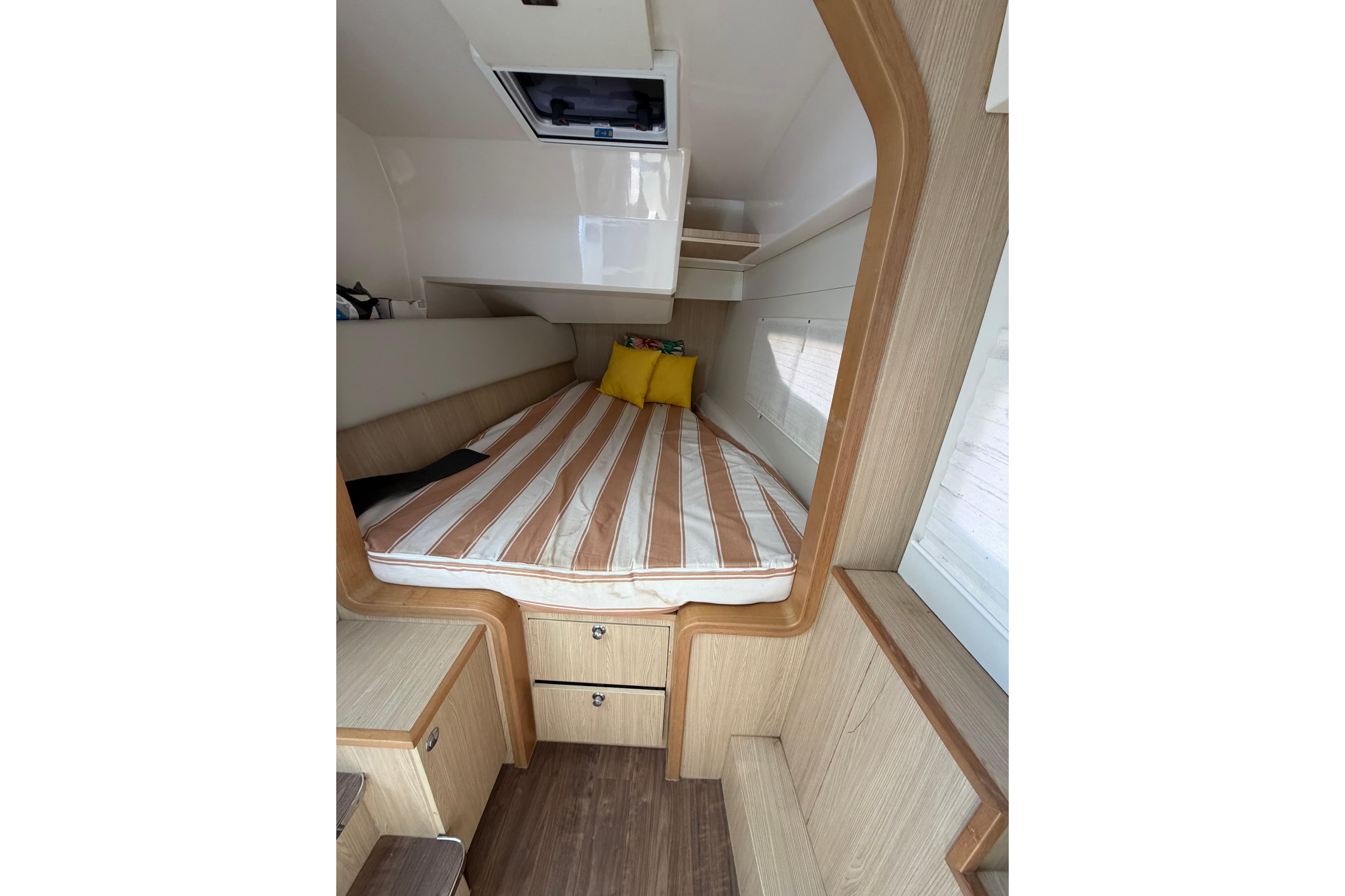 Interior cabin of 2018 Aquila 36 Sport with striped bedding and wooden accents.