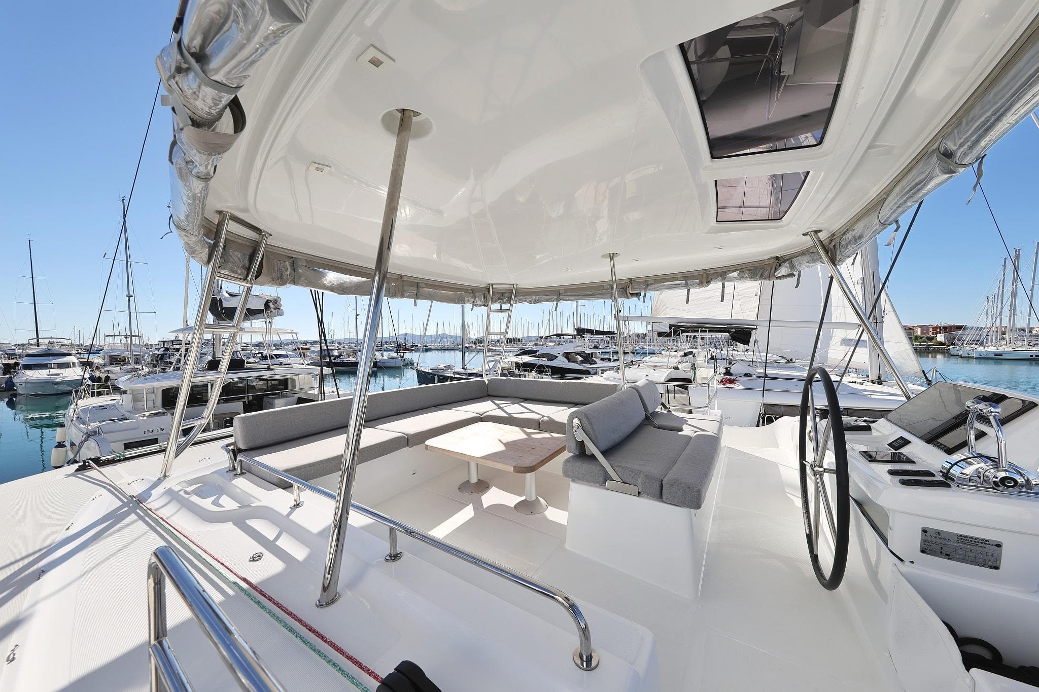 2024 Lagoon 51 yacht deck with seating and steering wheel in marina.