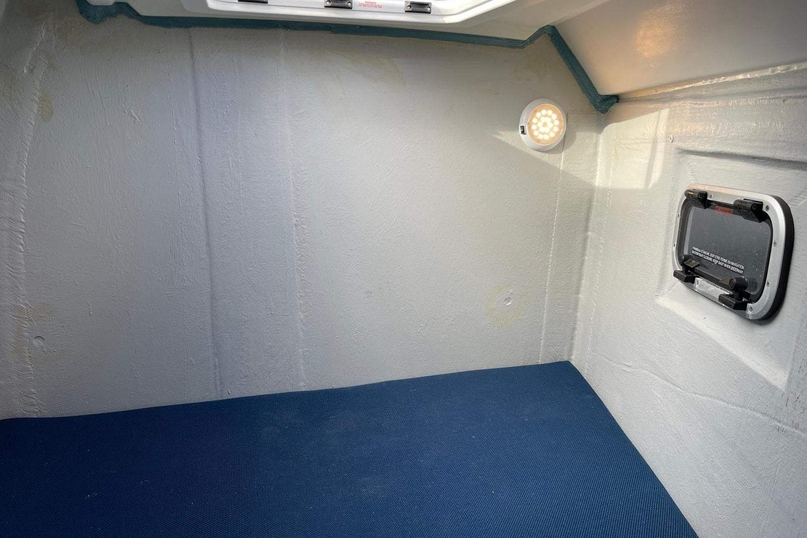 Interior cabin of 2023 Excess 11 boat with blue flooring and wall light.