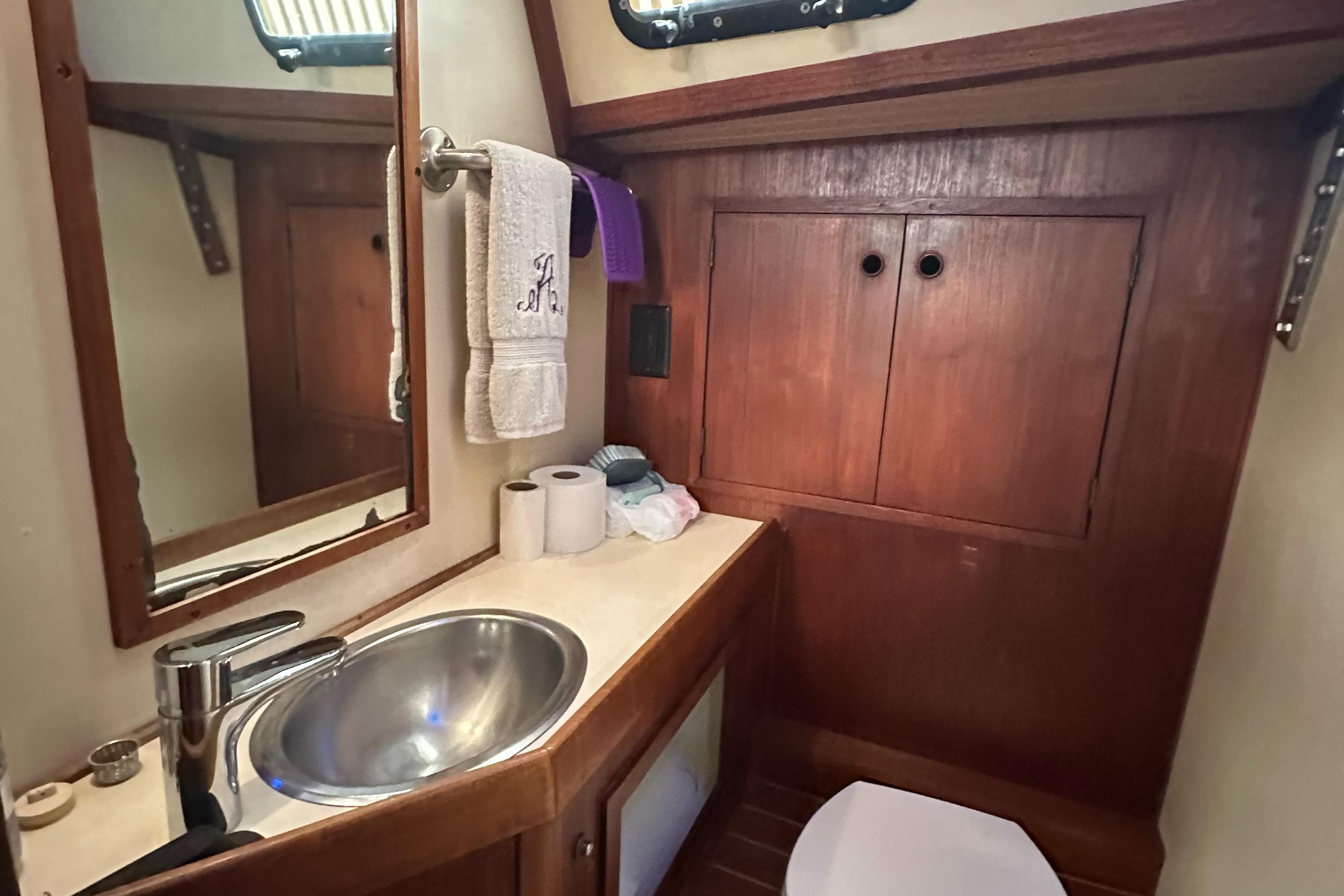 1979 Valiant 37 yacht bathroom with wooden cabinets and stainless steel sink.
