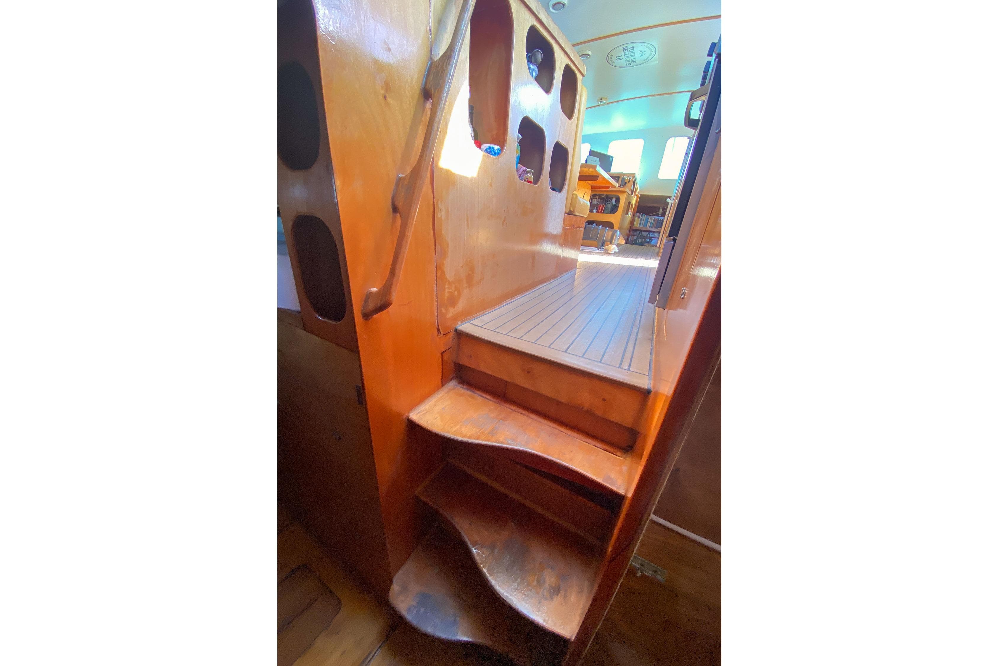 Wooden interior stairs on a 2004 BBL CAT 54 boat, leading to a sunlit cabin.