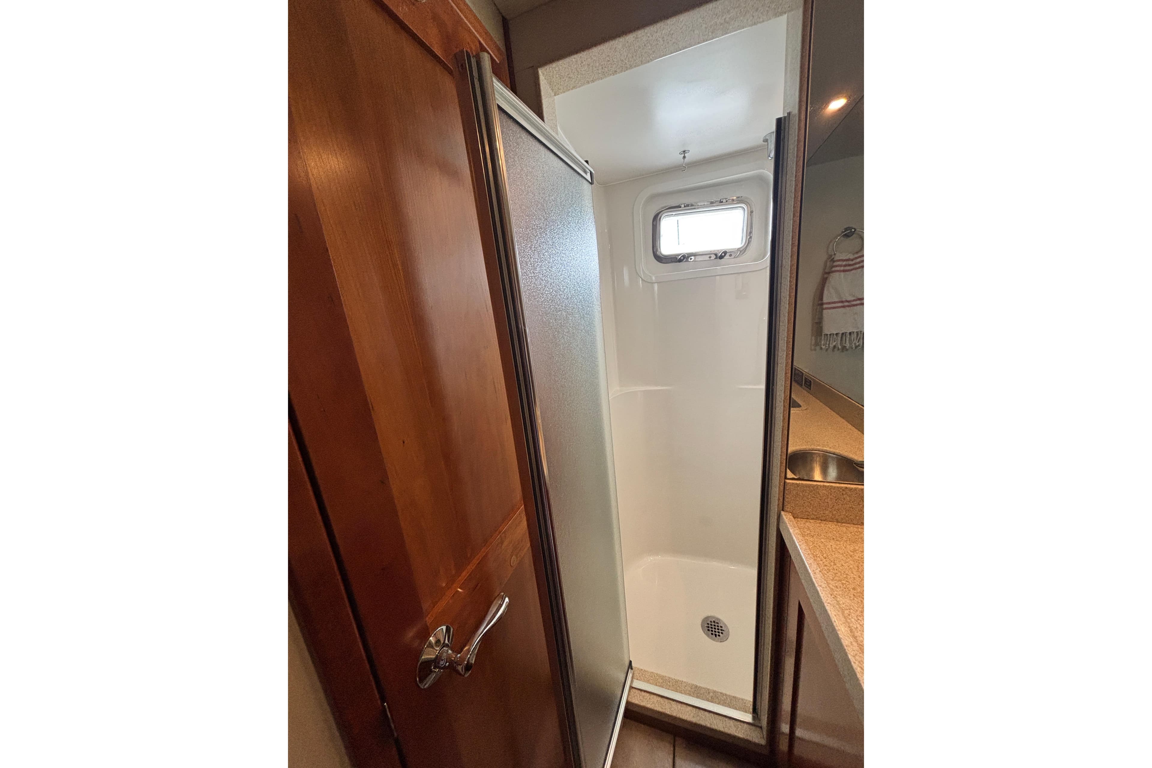 Shower area in 2006 Pilothouse Rockport Fast Trawler with wooden door and porthole window.