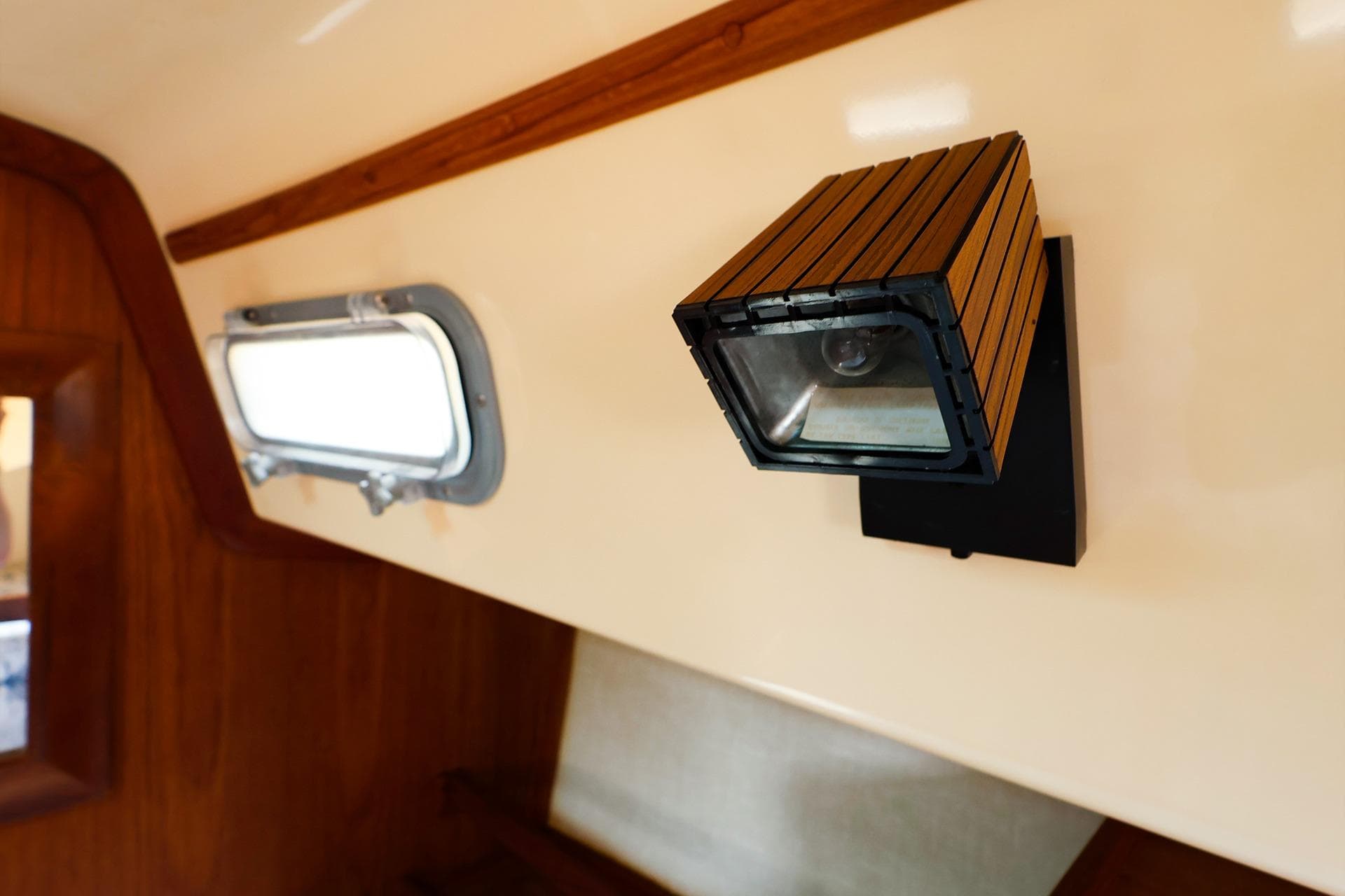 Interior of 1985 Island Packed 31 yacht with wooden light fixture and porthole.
