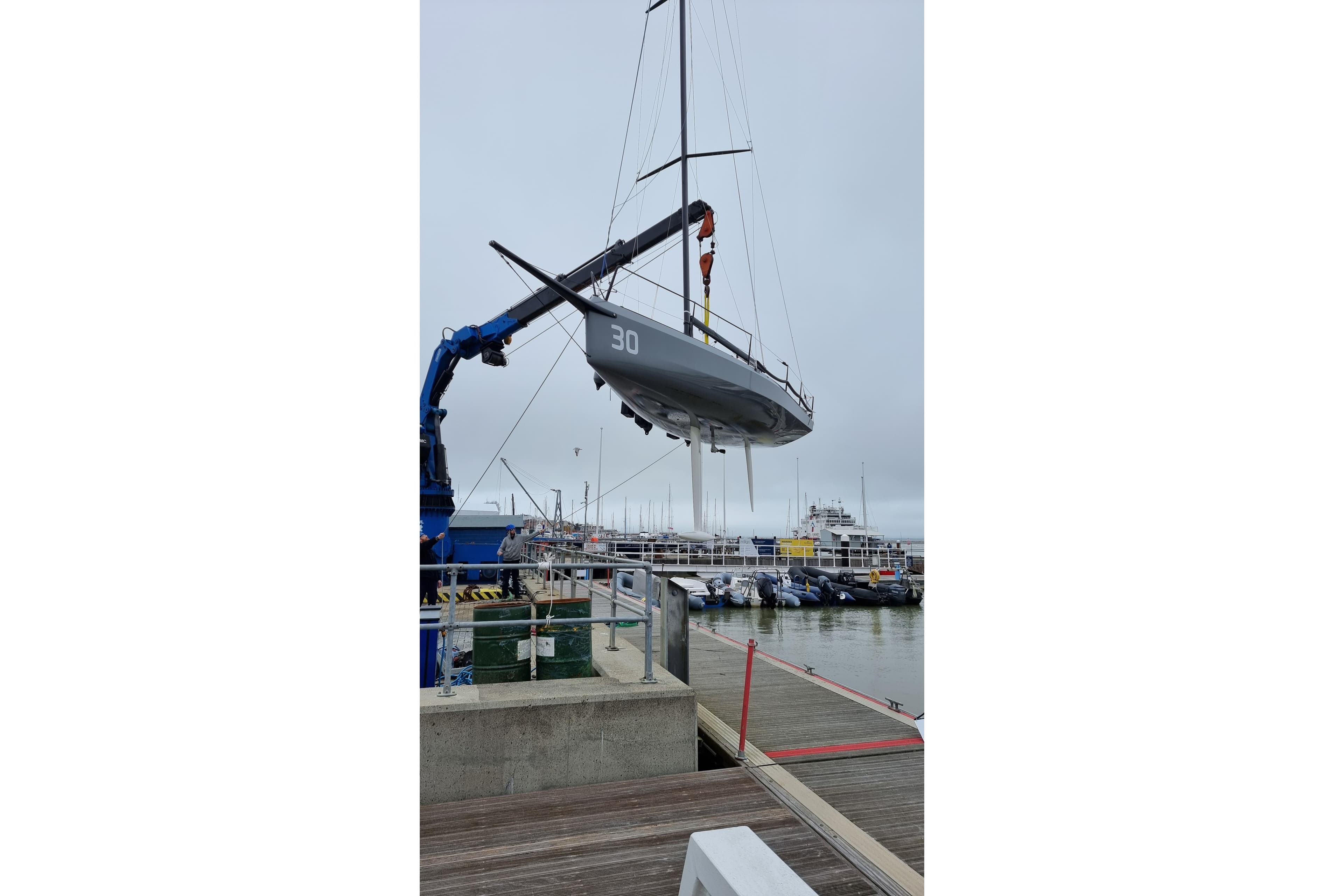 Sailboat "One Design Cape31" being lifted by crane at marina, 2022 model.