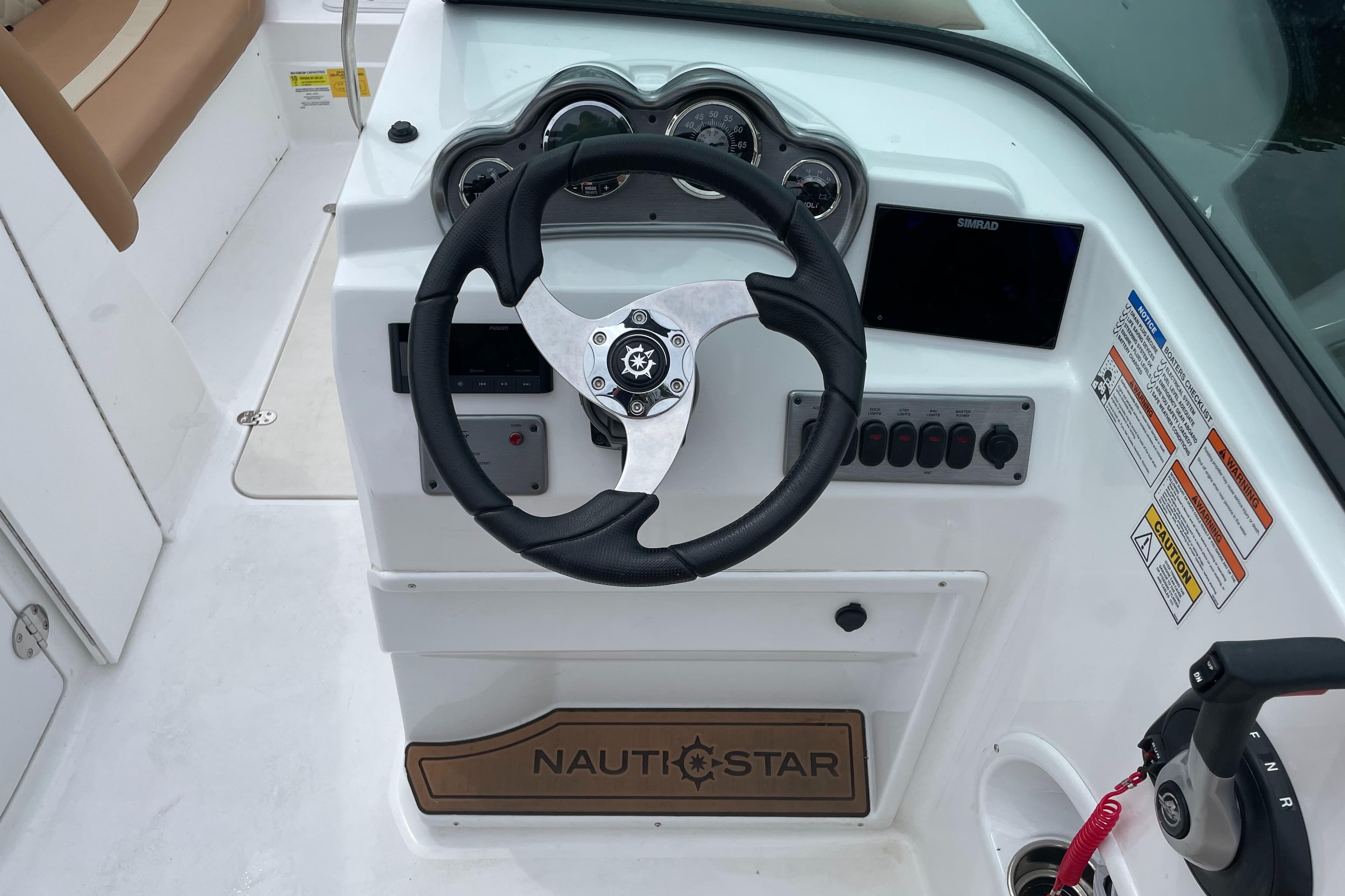 2025 NauticStar 223 DC Deck boat steering console with gauges and controls.