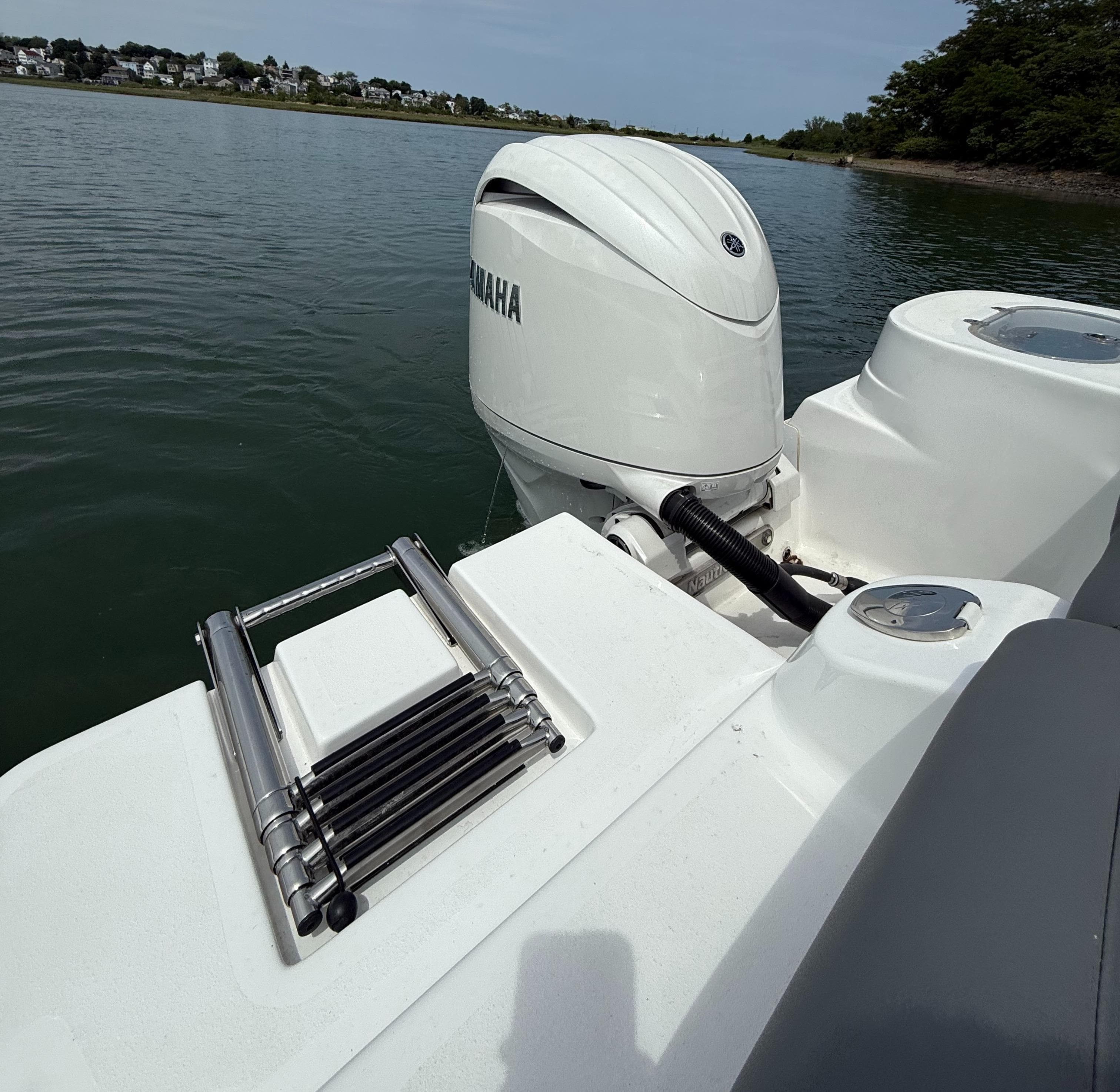 2025 NauticStar 212 Legacy boat with Yamaha outboard motor and swim ladder on calm water.
