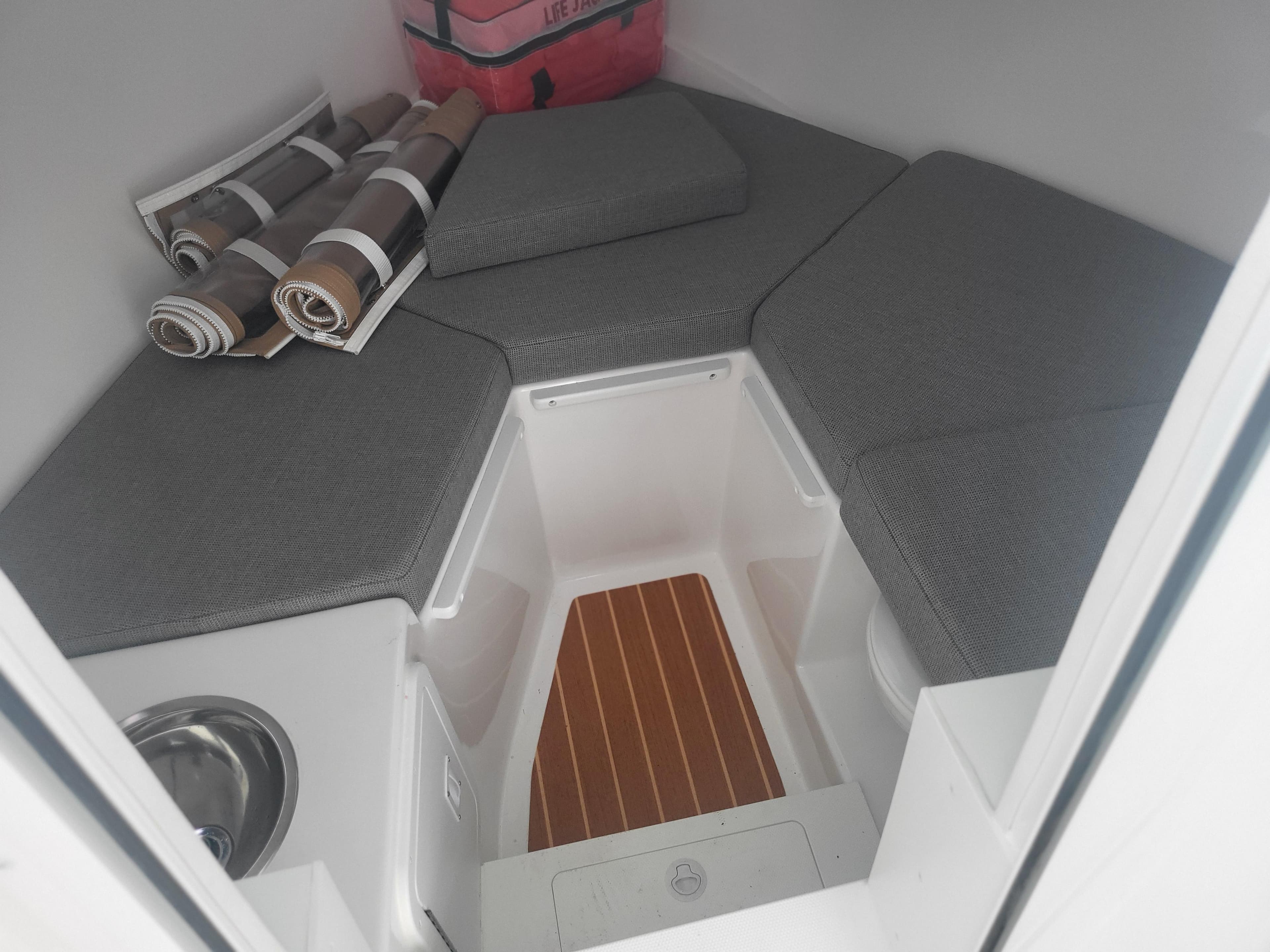 2025 Steiger Craft 28 Fisherman cabin interior with gray cushions and wooden flooring.