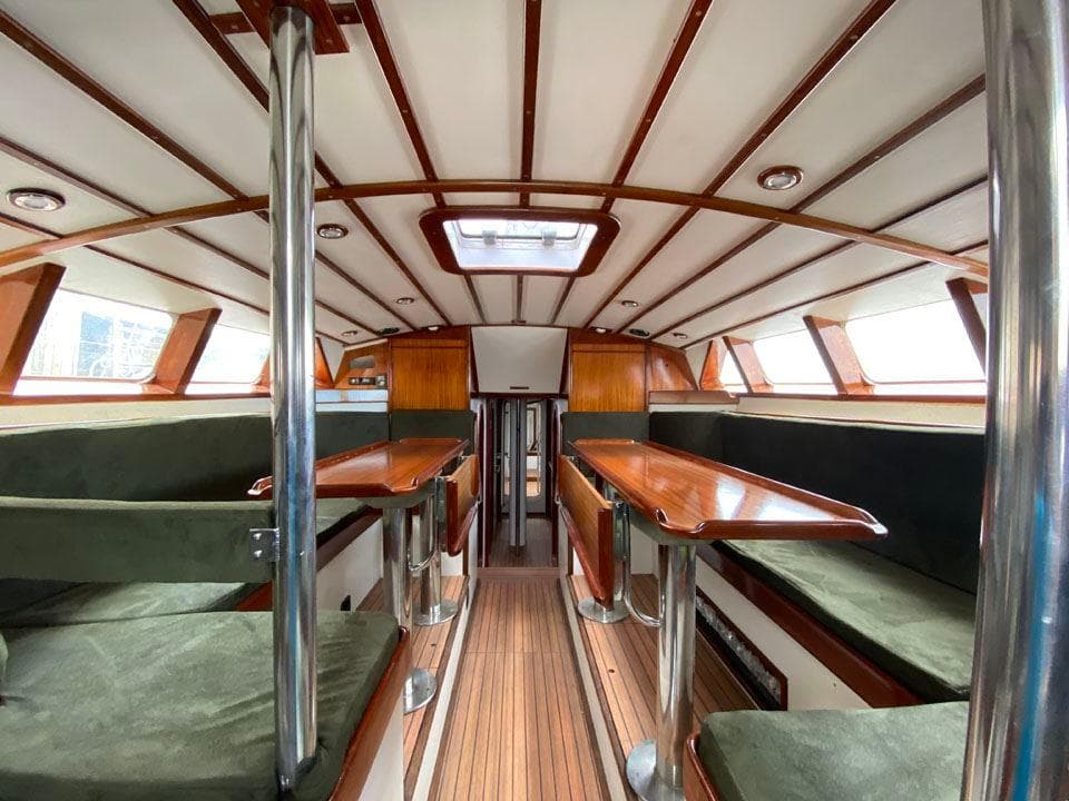 Interior of 1995 Devonport Challenge 67 yacht with wooden tables and green seating.