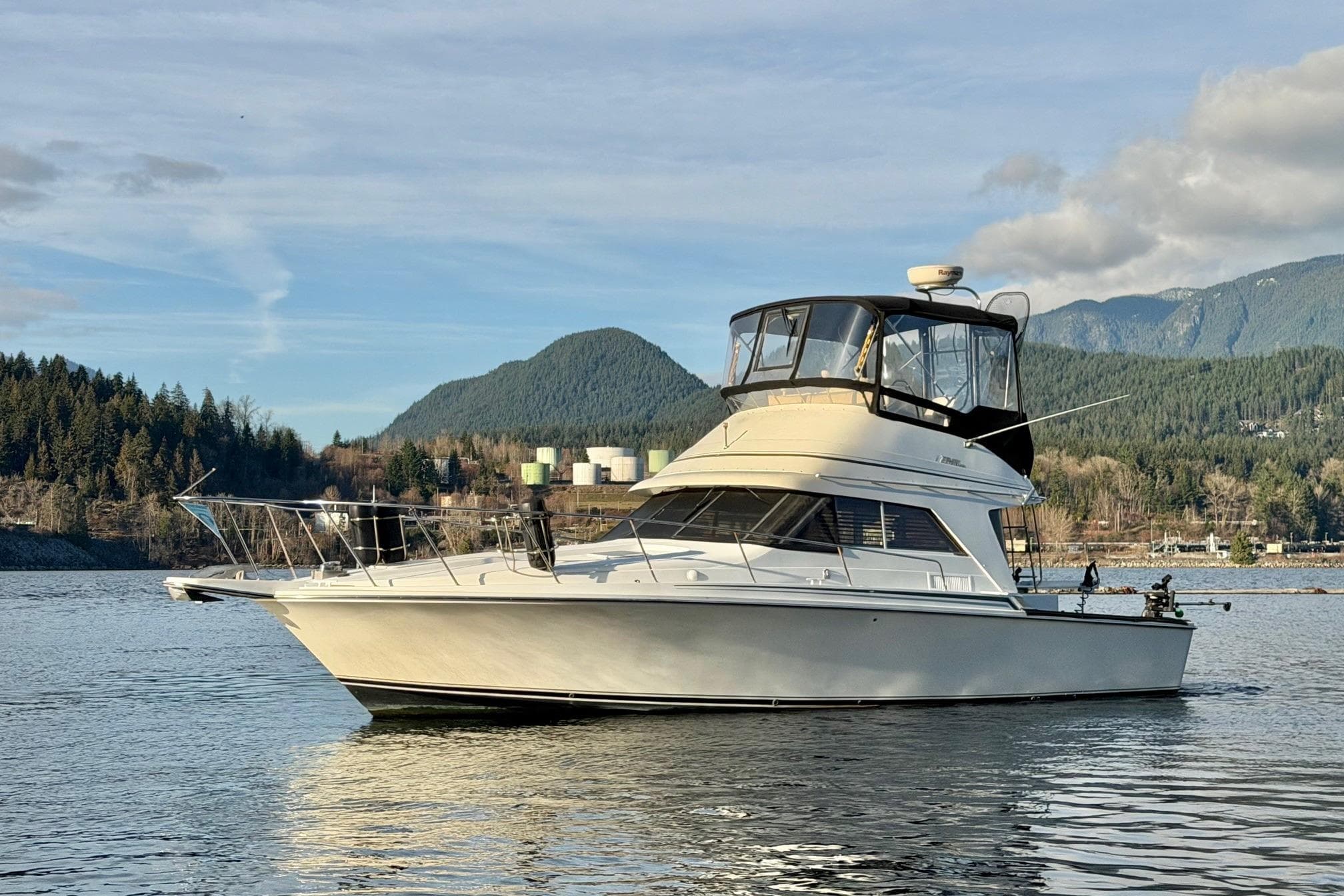 1990 Trojan 10.8 Meter Sedan boat on scenic lake with mountain backdrop.