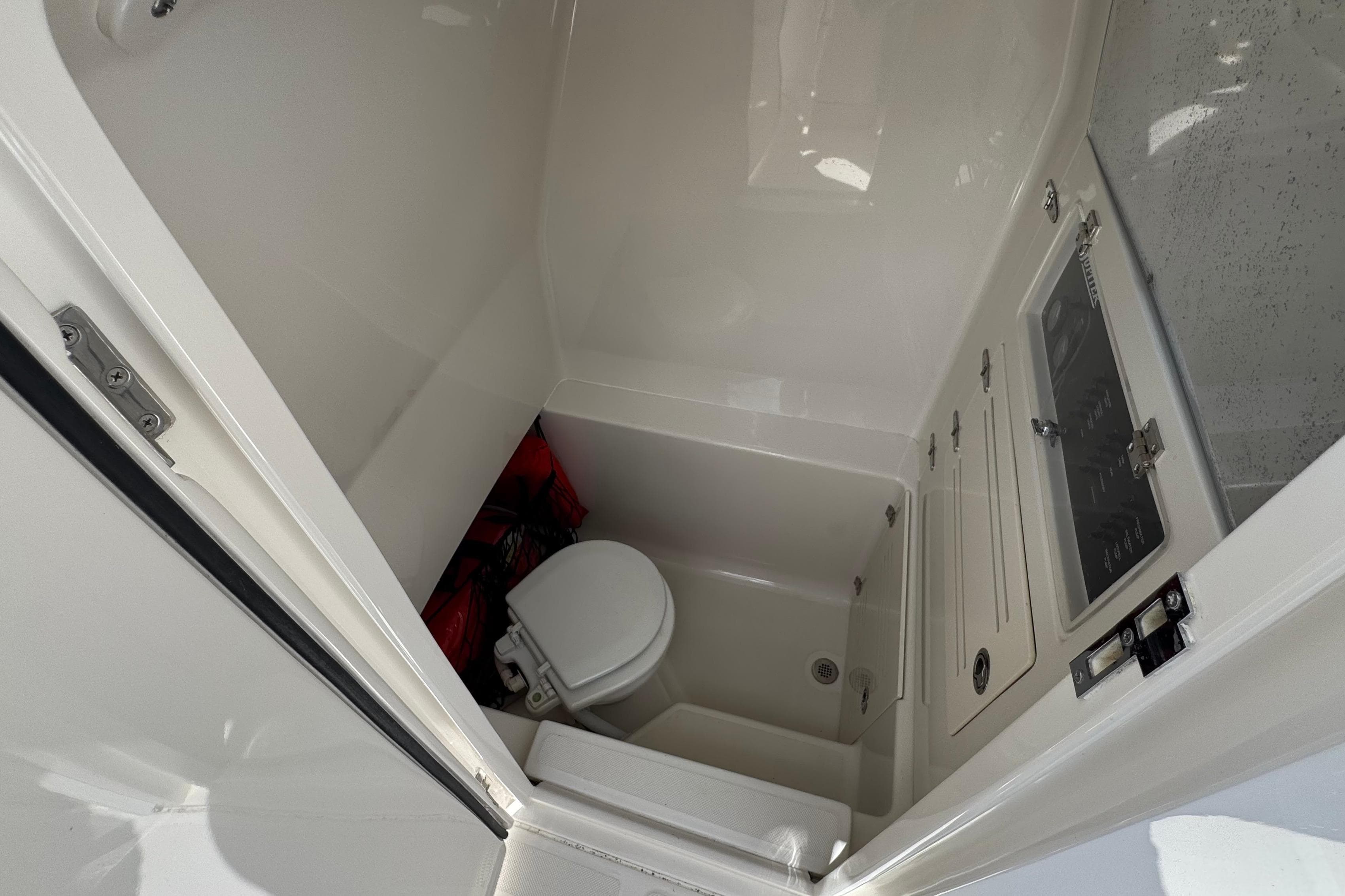 Interior of 2013 Jupiter 32 Cuddy boat showing compact bathroom with toilet and storage.