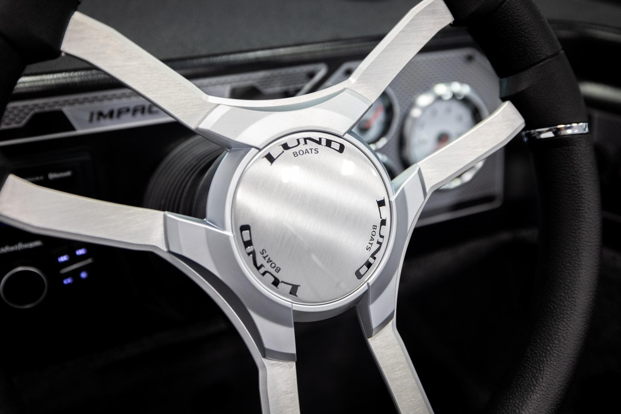 Steering wheel of 2026 Lund 2075 Impact XS boat, featuring sleek metallic design.