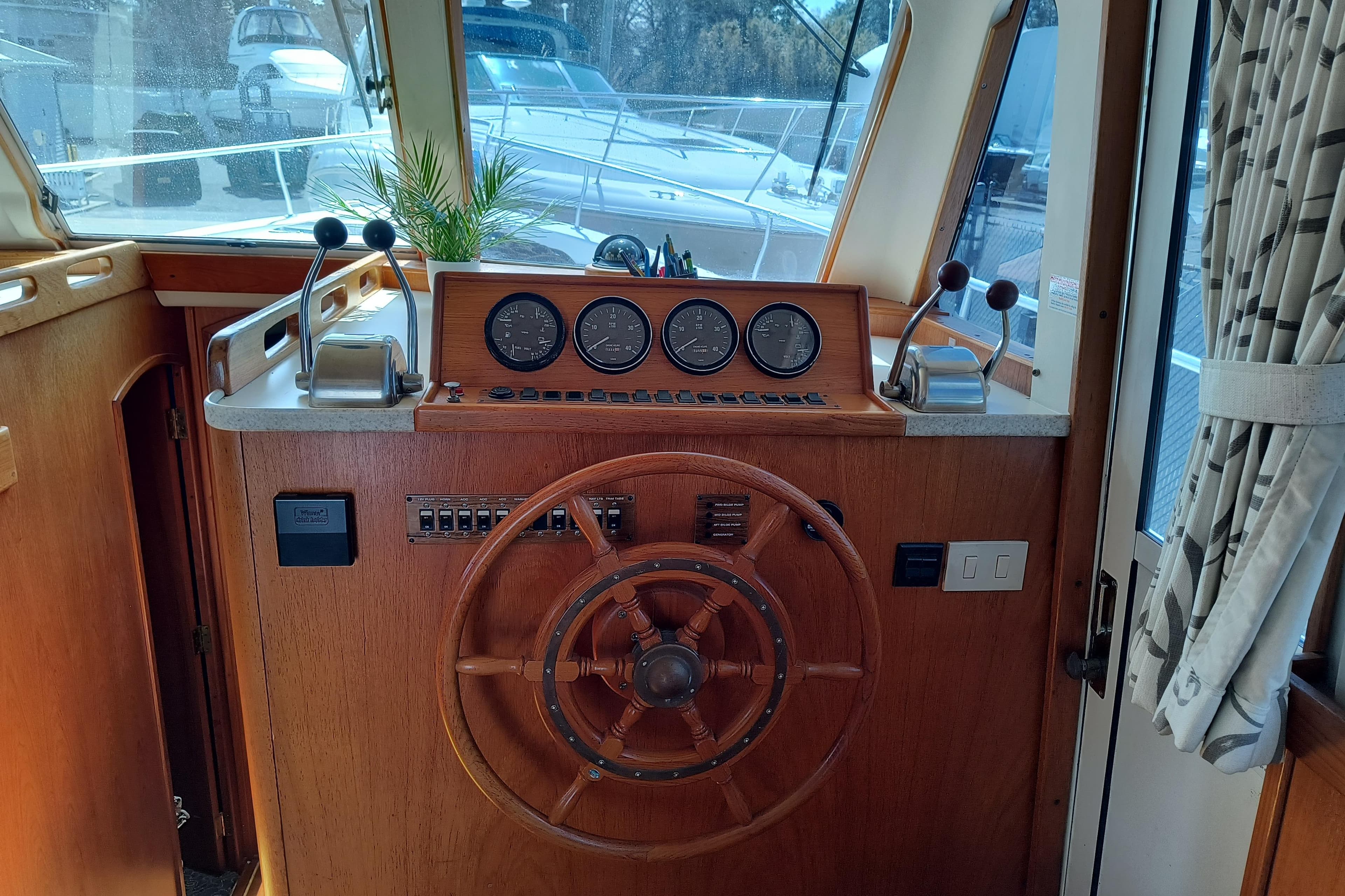 2000 Mainship 390 Trawler helm with wooden steering wheel and control panel.
