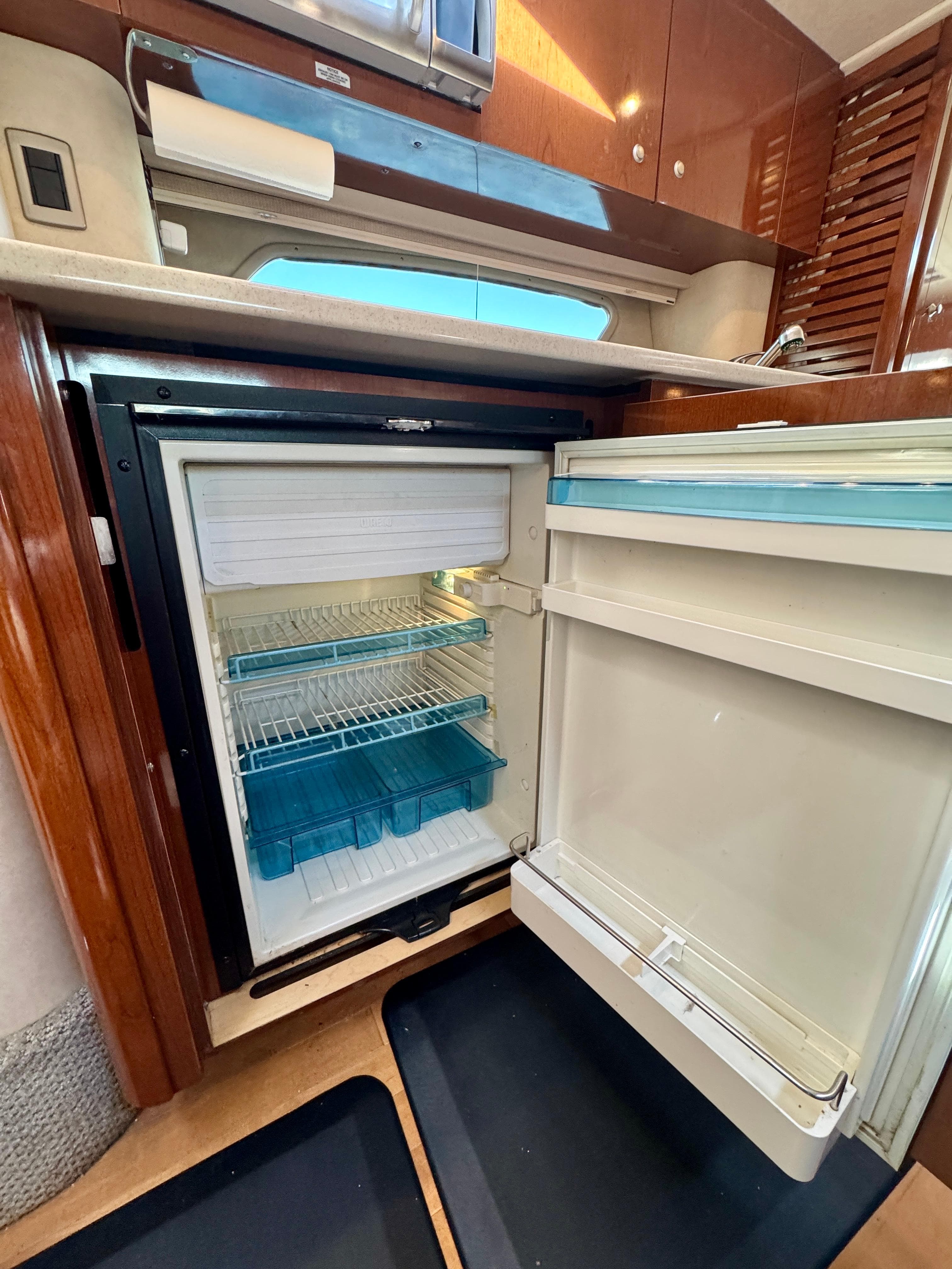 2009 Sea Ray 350 Sundancer interior with open refrigerator, showcasing modern kitchen amenities.