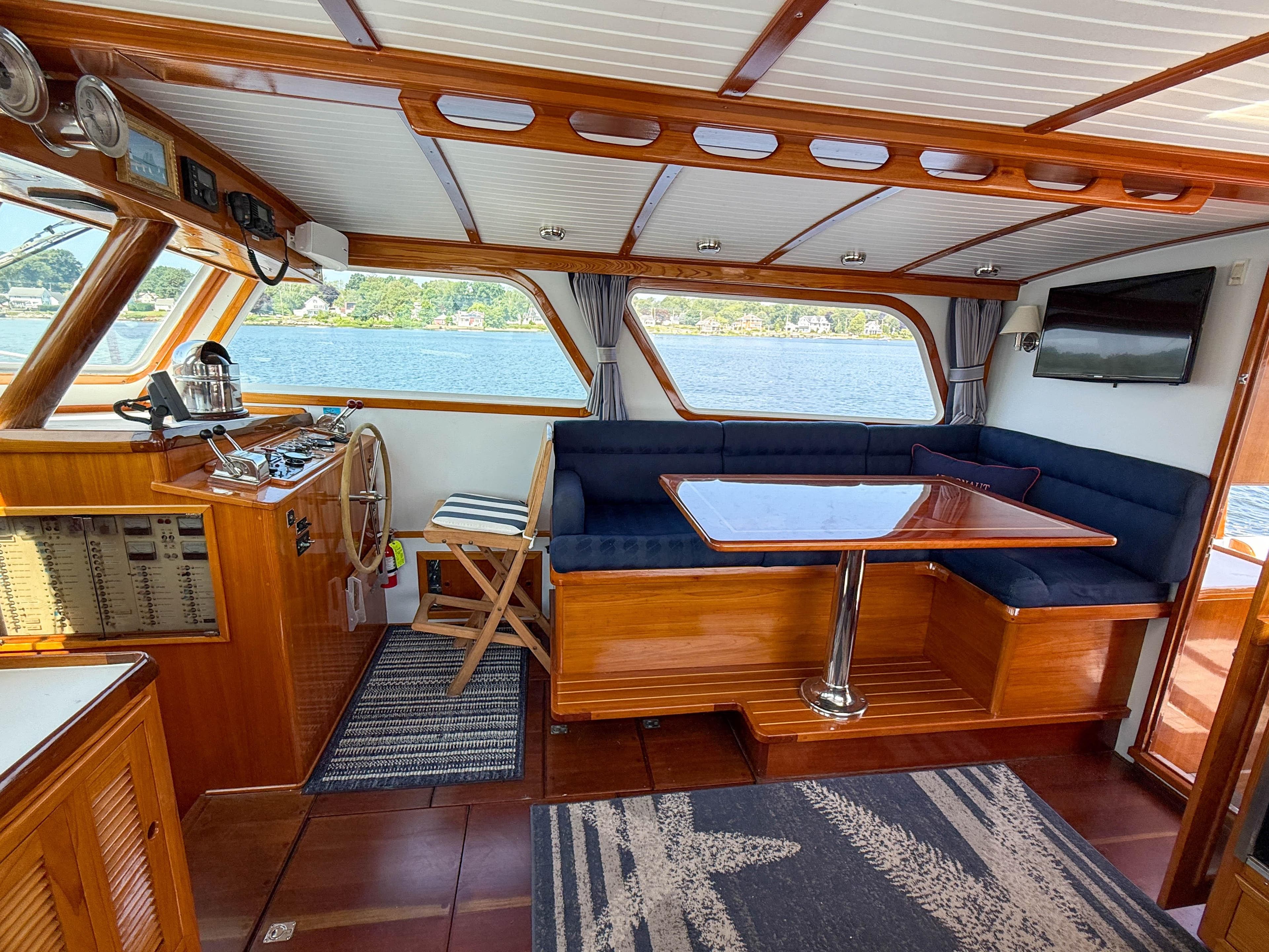 Interior of 1984 Wilbur 38 boat with wooden finish, blue seating, and steering wheel.