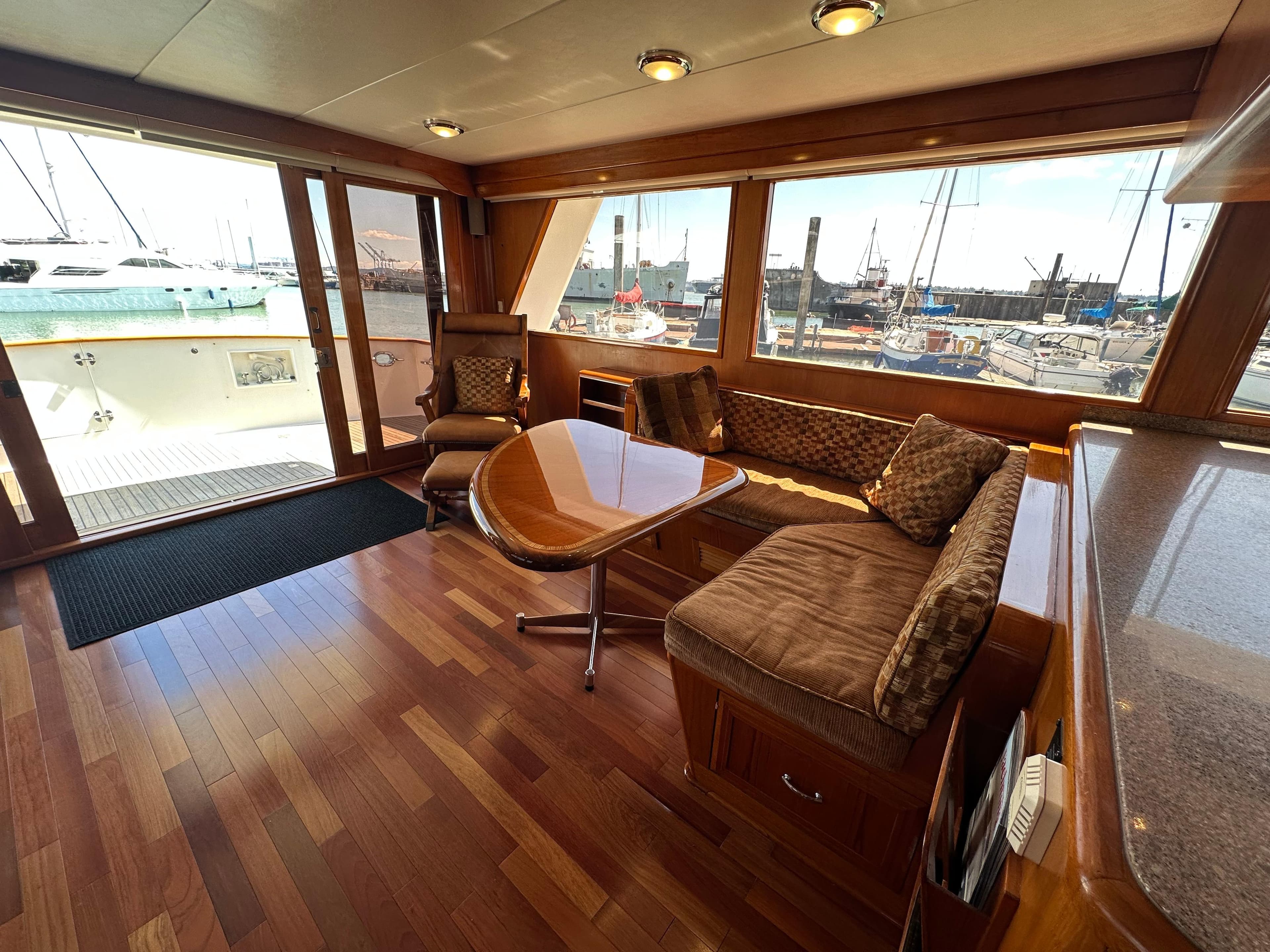 Luxurious 1985 Ocean Alexander Pilothouse interior with wood flooring and marina view.