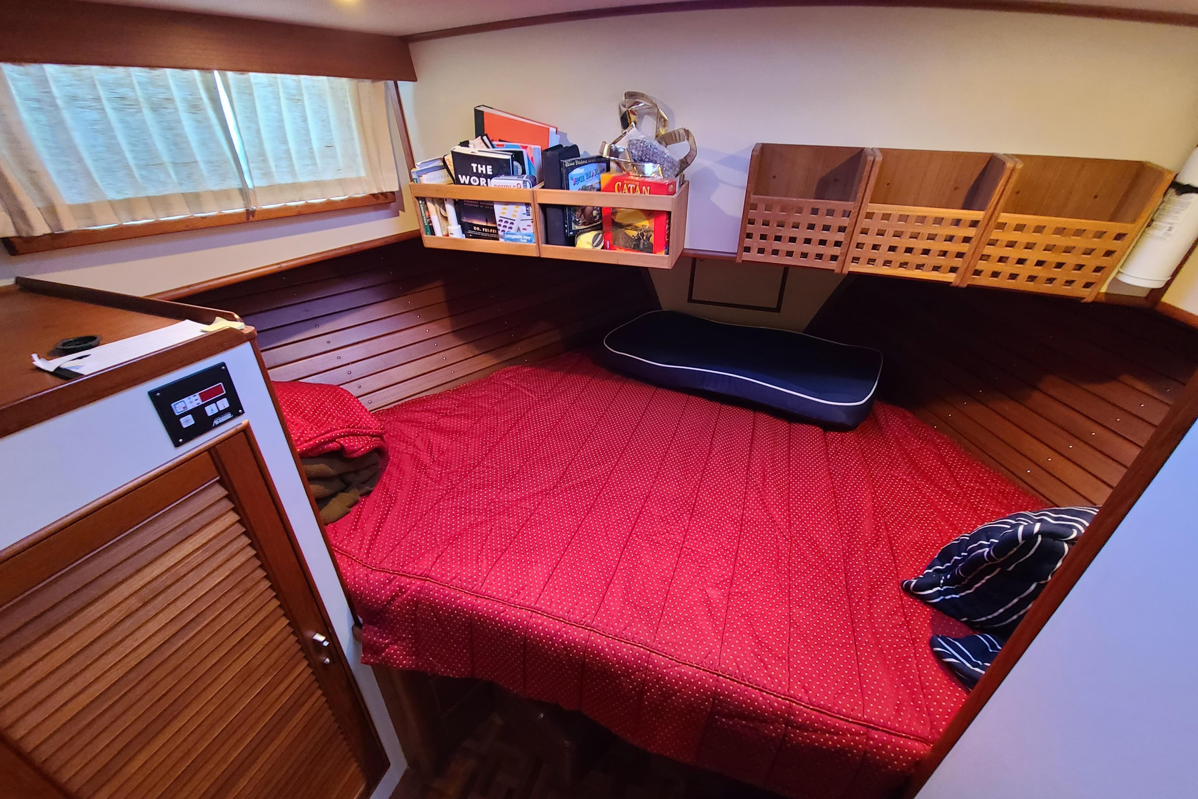 Cozy cabin interior of 2000 Grand Banks 46 Classic yacht with red bedding.