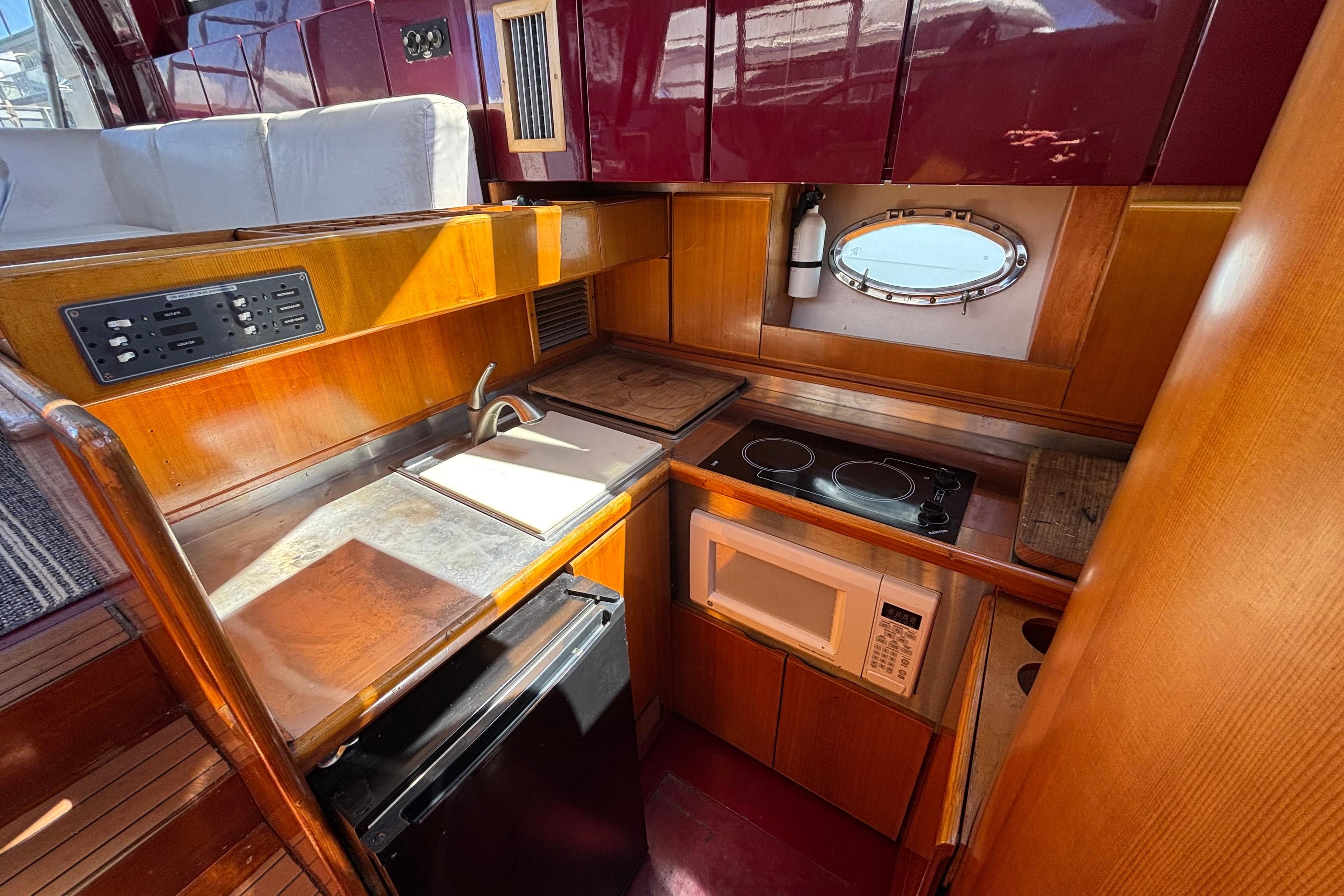 1984 Posillipo Technema yacht kitchen with stove, microwave, and wooden cabinetry.