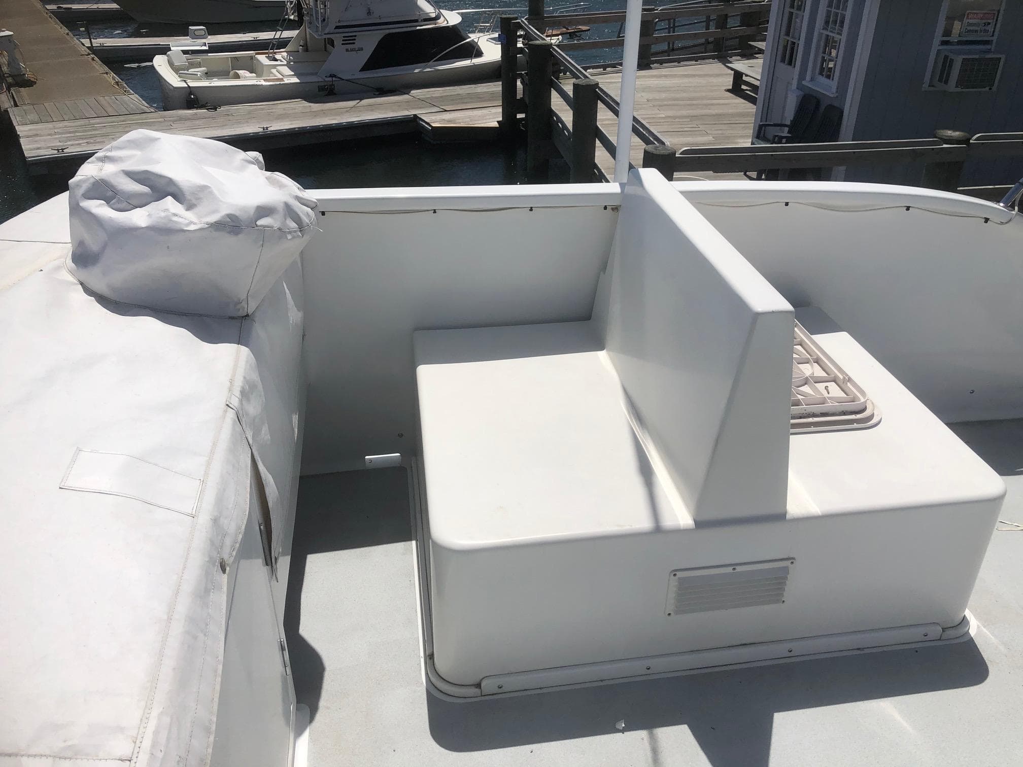 2003 Wesmac Flybridge boat with white seating area at the dock.