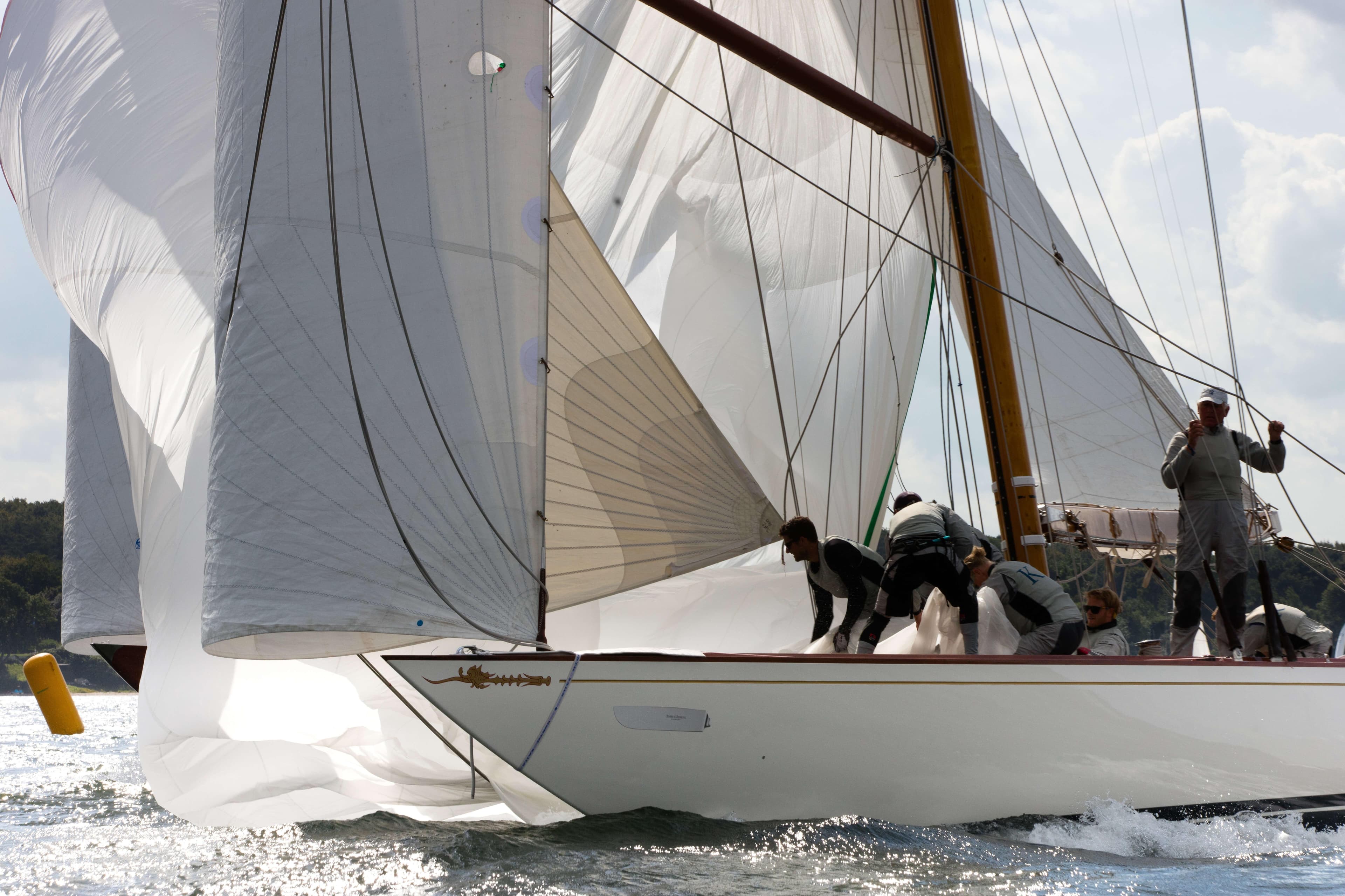 Classic 1936 William Fife 12mR Class yacht sailing with crew adjusting sails.