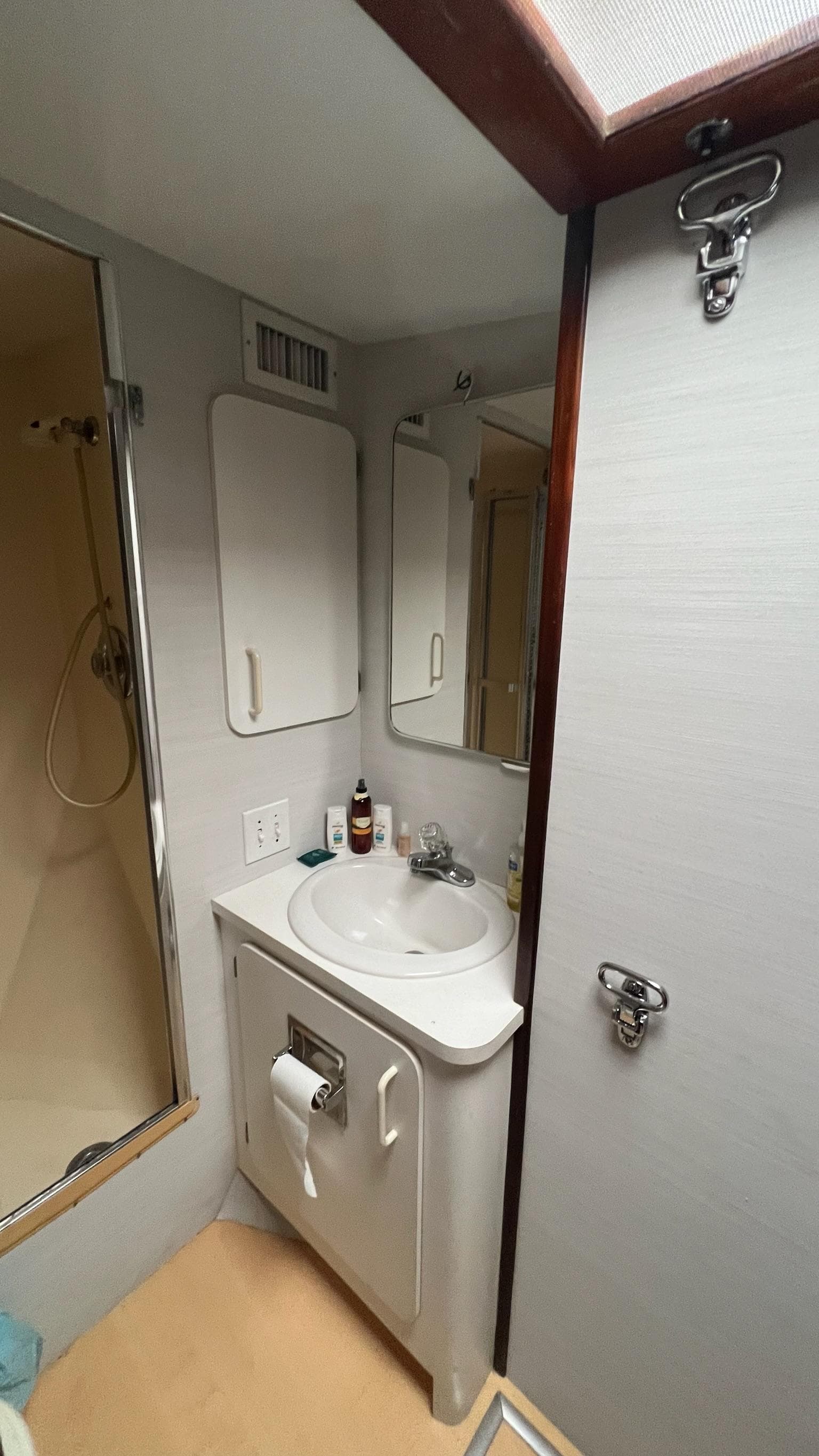 1987 Hatteras Motoryacht bathroom with sink, mirror, and shower.