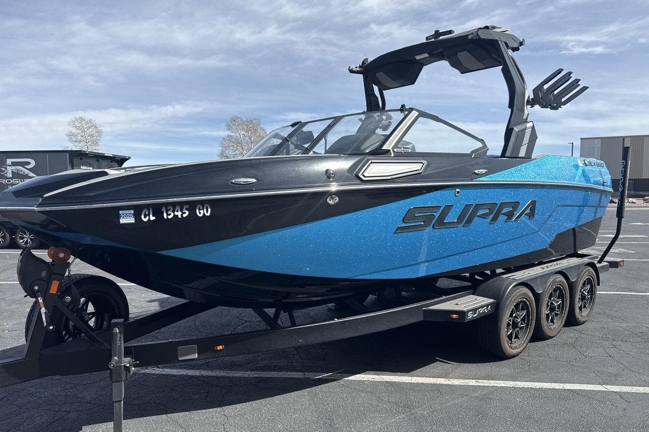 2024 Supra SL 550 boat on trailer in parking lot, blue and black design.