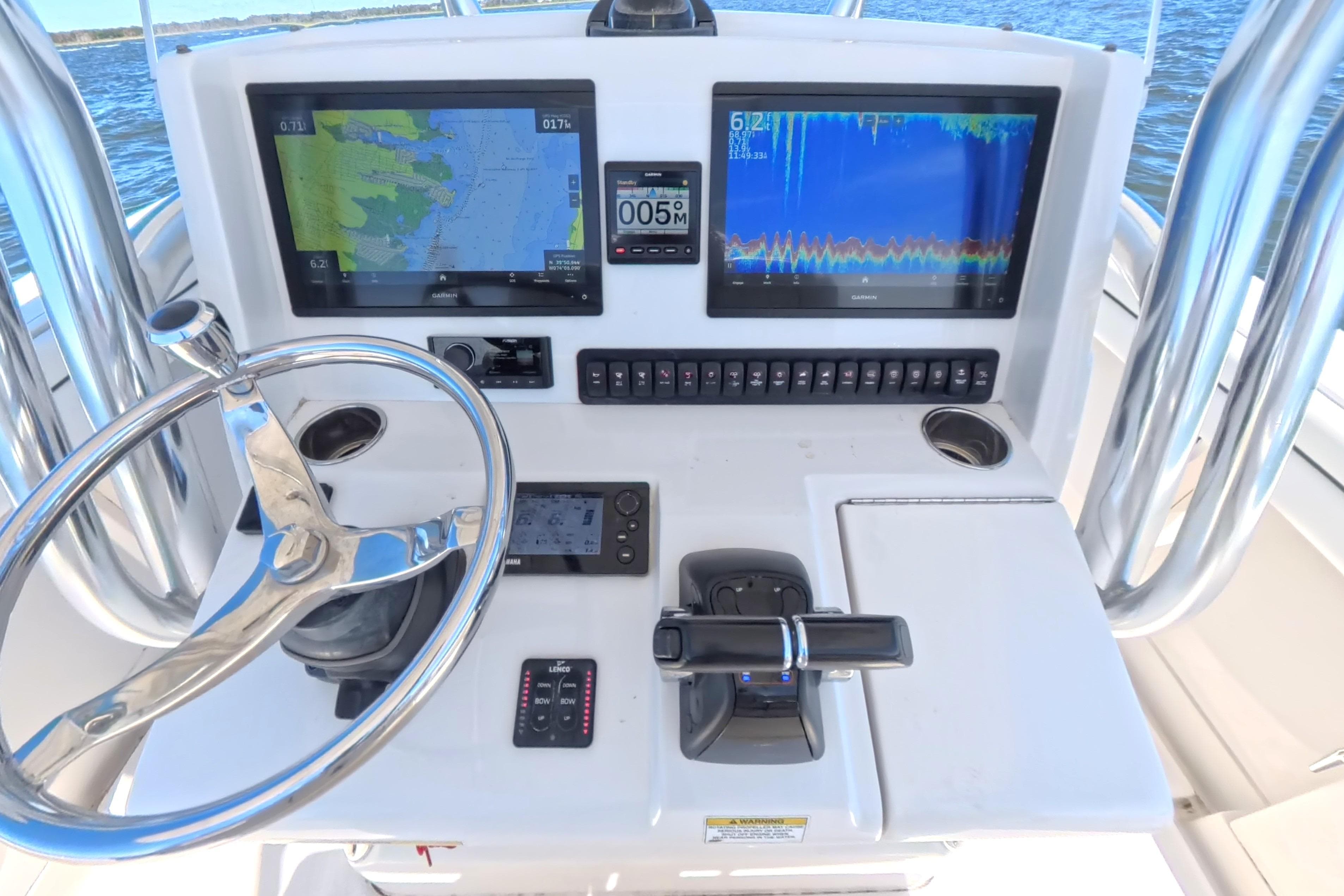 Control panel of a 2014 Jupiter 30 FS boat with navigation screens and steering wheel.