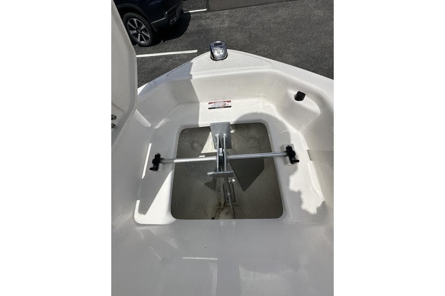 2023 Chaparral 23 Surf boat anchor compartment with metal fittings and white interior.
