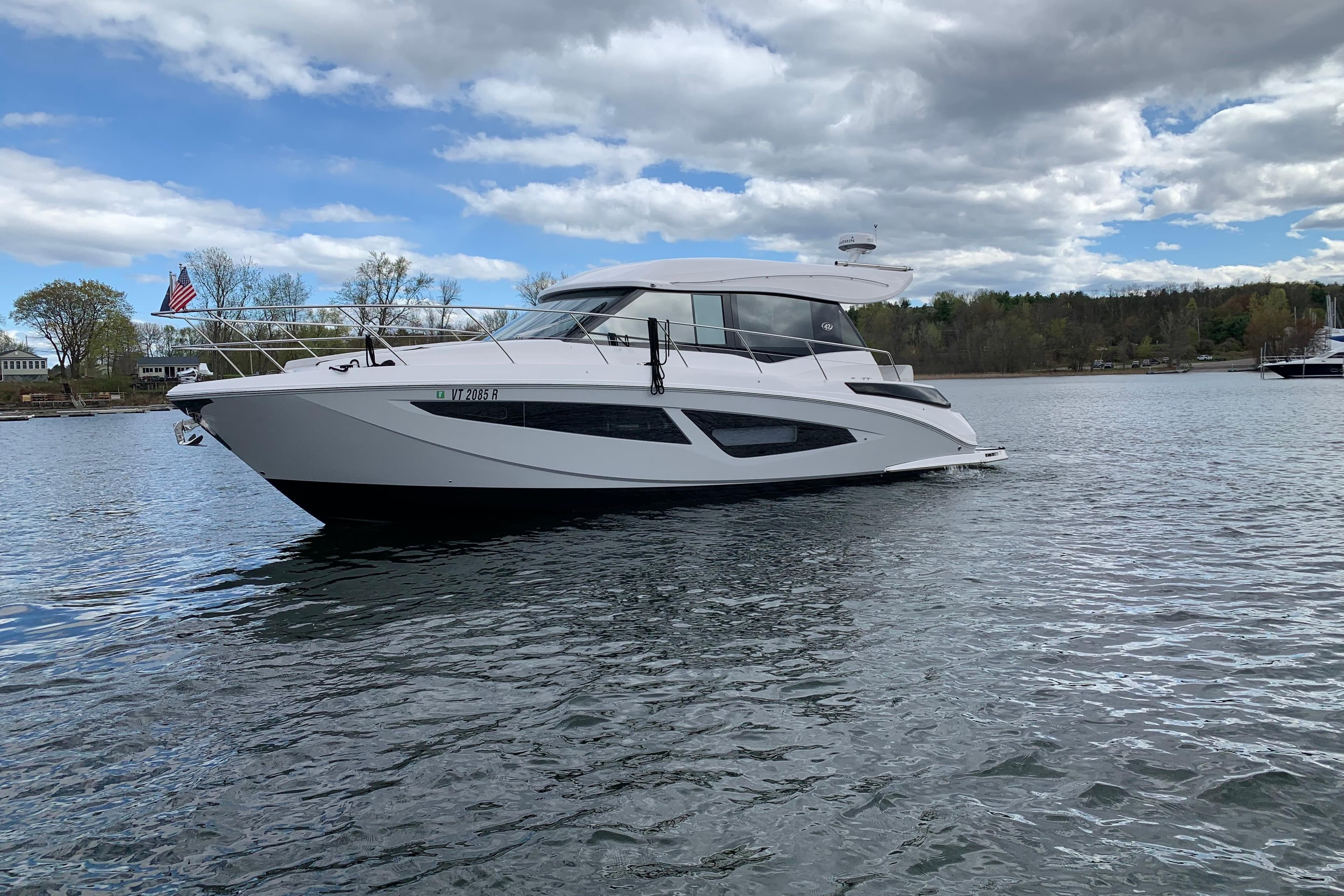 2019 Regal 42 Grande Coupe yacht on a serene lake under a cloudy sky.