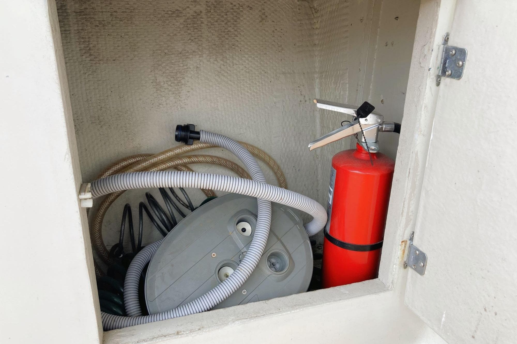Storage compartment on 1980 Tollycraft 34 Sedan with hoses and fire extinguisher.