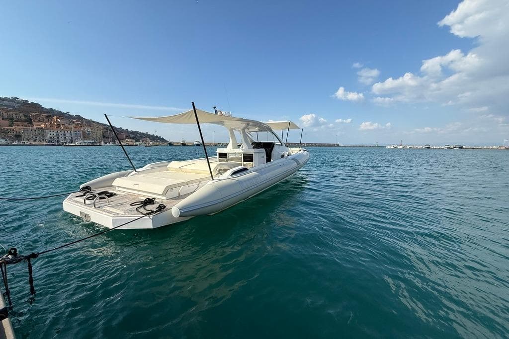 2022 Pirelli PIRELLI 42 yacht docked in a scenic harbor under a clear blue sky.