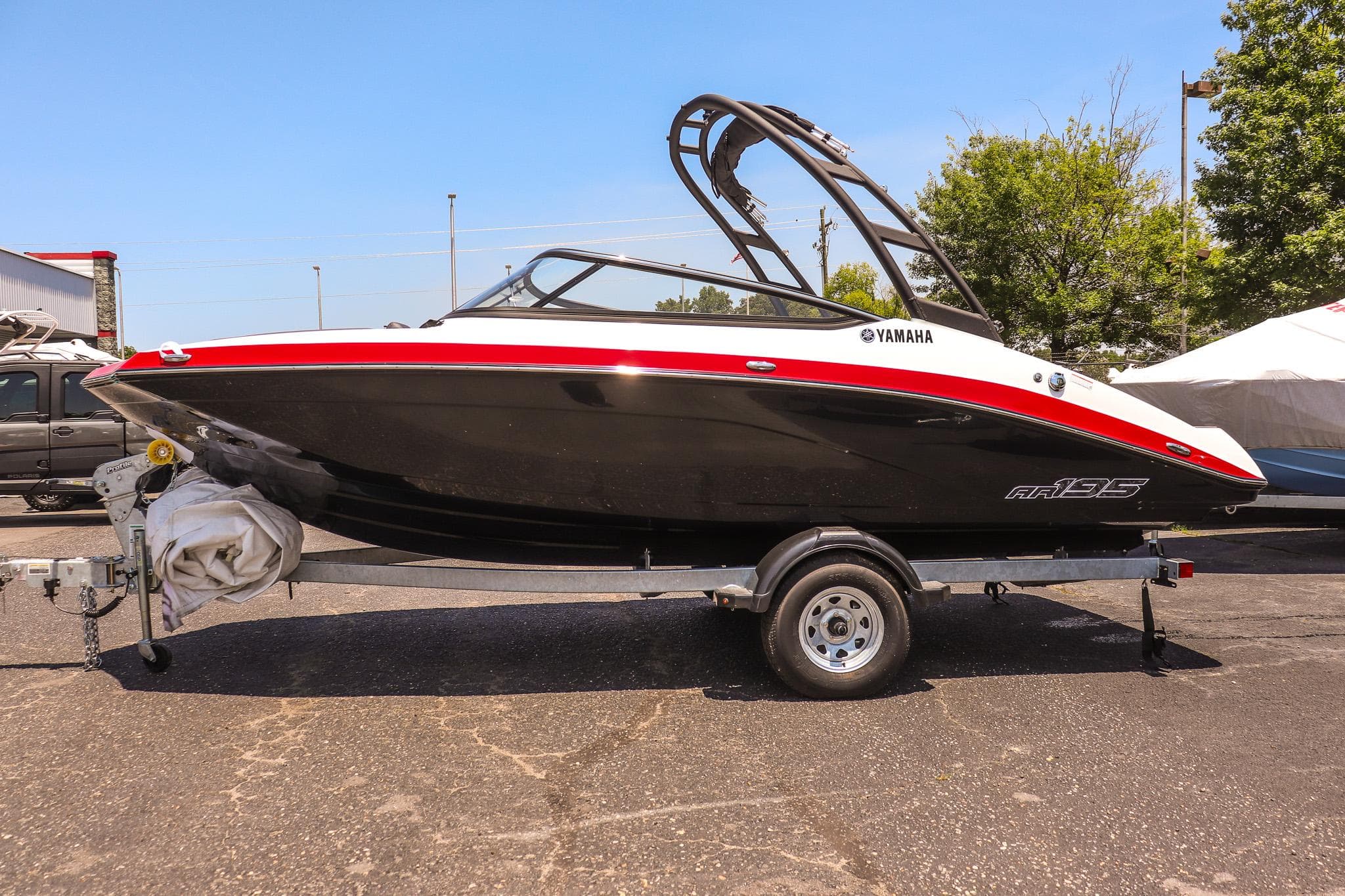2025 Yamaha AR195 boat on trailer, black and red design, parked outdoors.