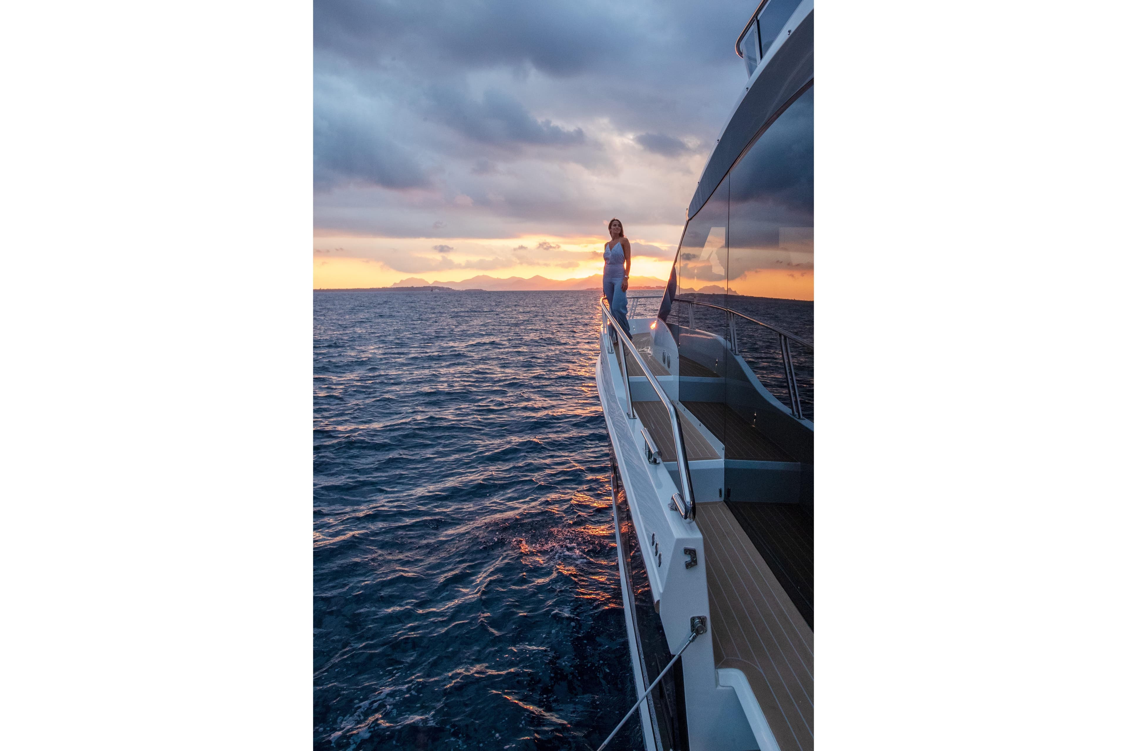 2026 Galeon 560 Fly yacht at sunset, woman standing on deck, ocean view.