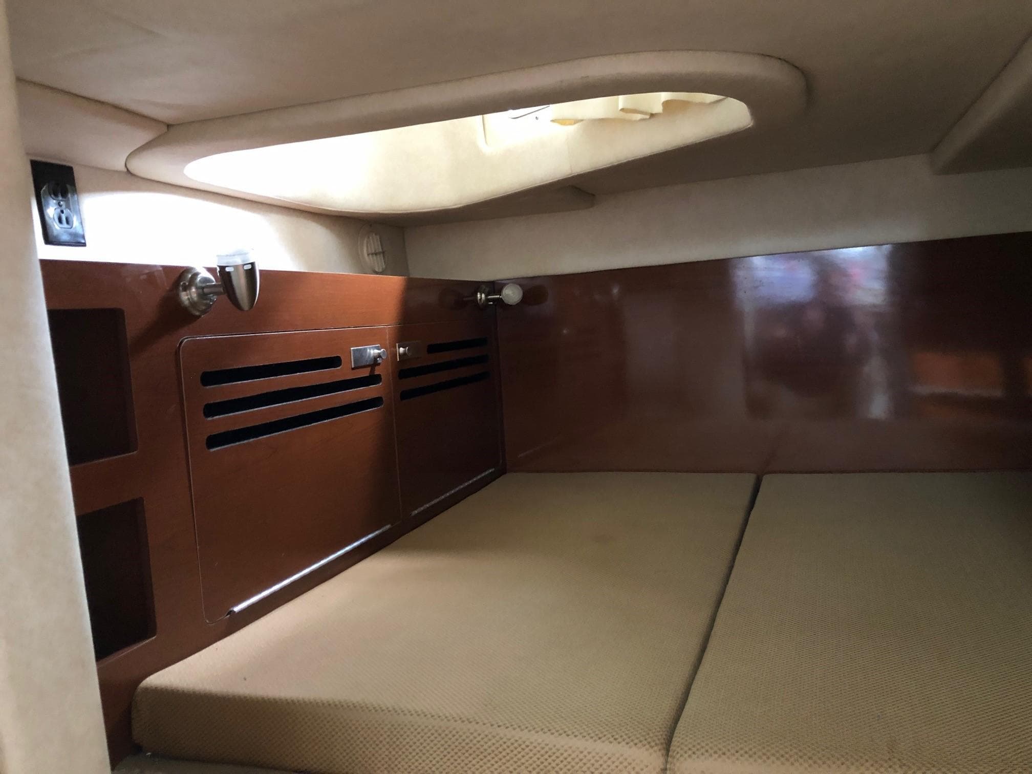 Interior cabin of 2009 Sea Ray 270 Sundancer with cushioned bed and wooden storage.
